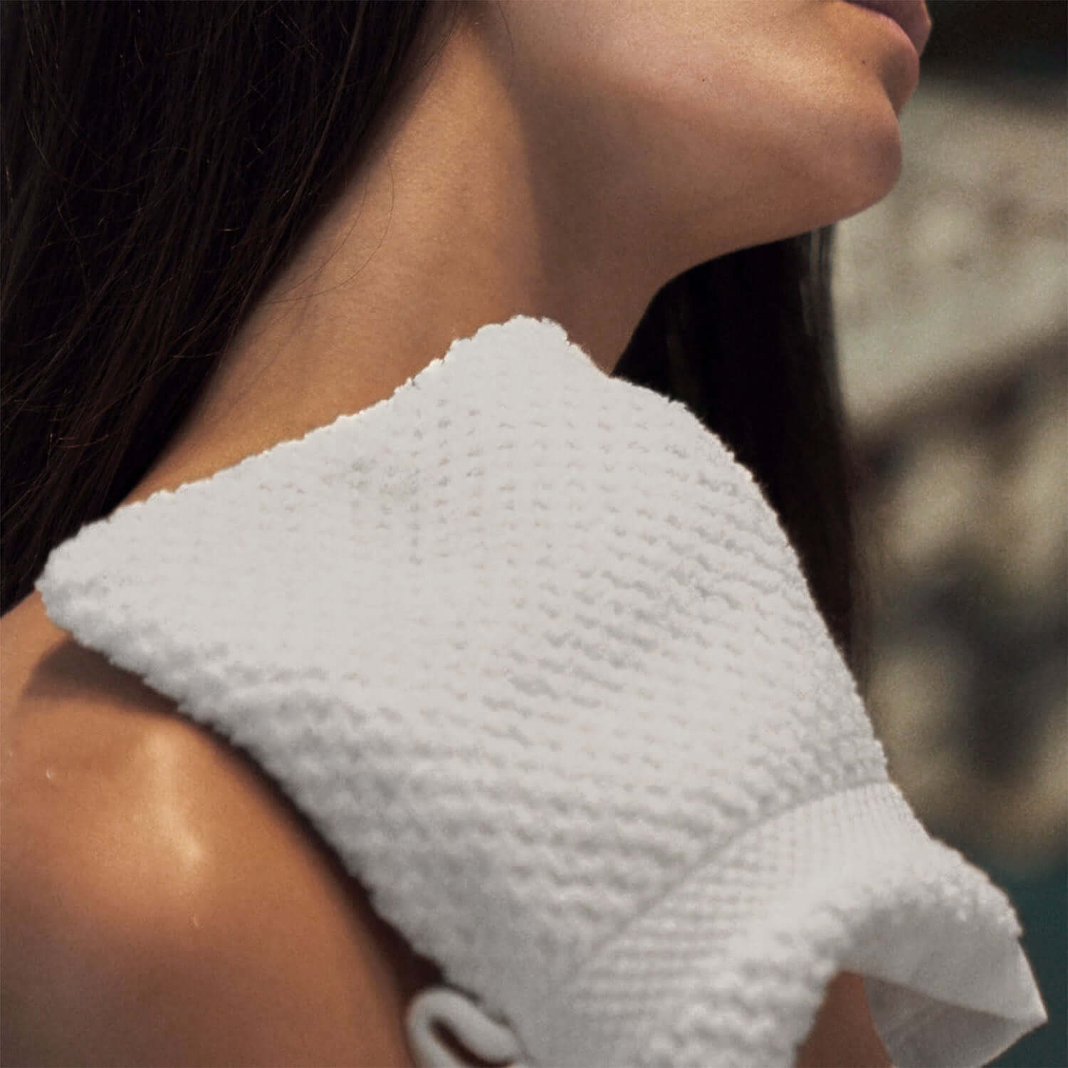 Close-up of a model wearing a textured white Novotel Glove on her shoulder, highlighting its luxurious feel and design.