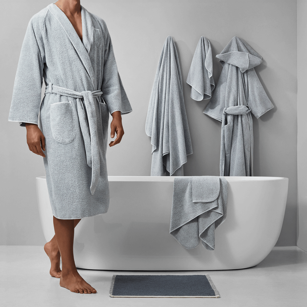 Stylish bathroom scene with a man in a gray robe, elegant bathtub, and neatly hung towels for a serene atmosphere.