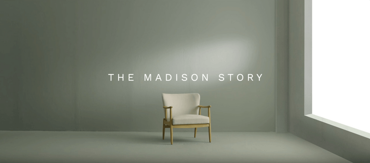 Minimalist interior featuring a light chair against a grey wall, with the text "THE MADISON STORY" in view.