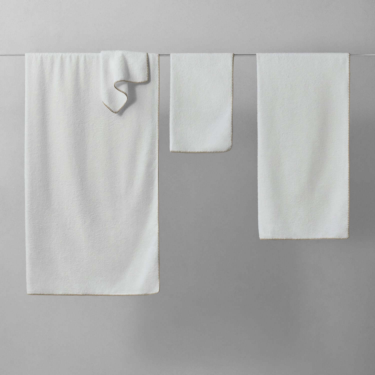 Bordado Towel Sand Trim, thin plush towels on display, eco-friendly design uses less water and space.