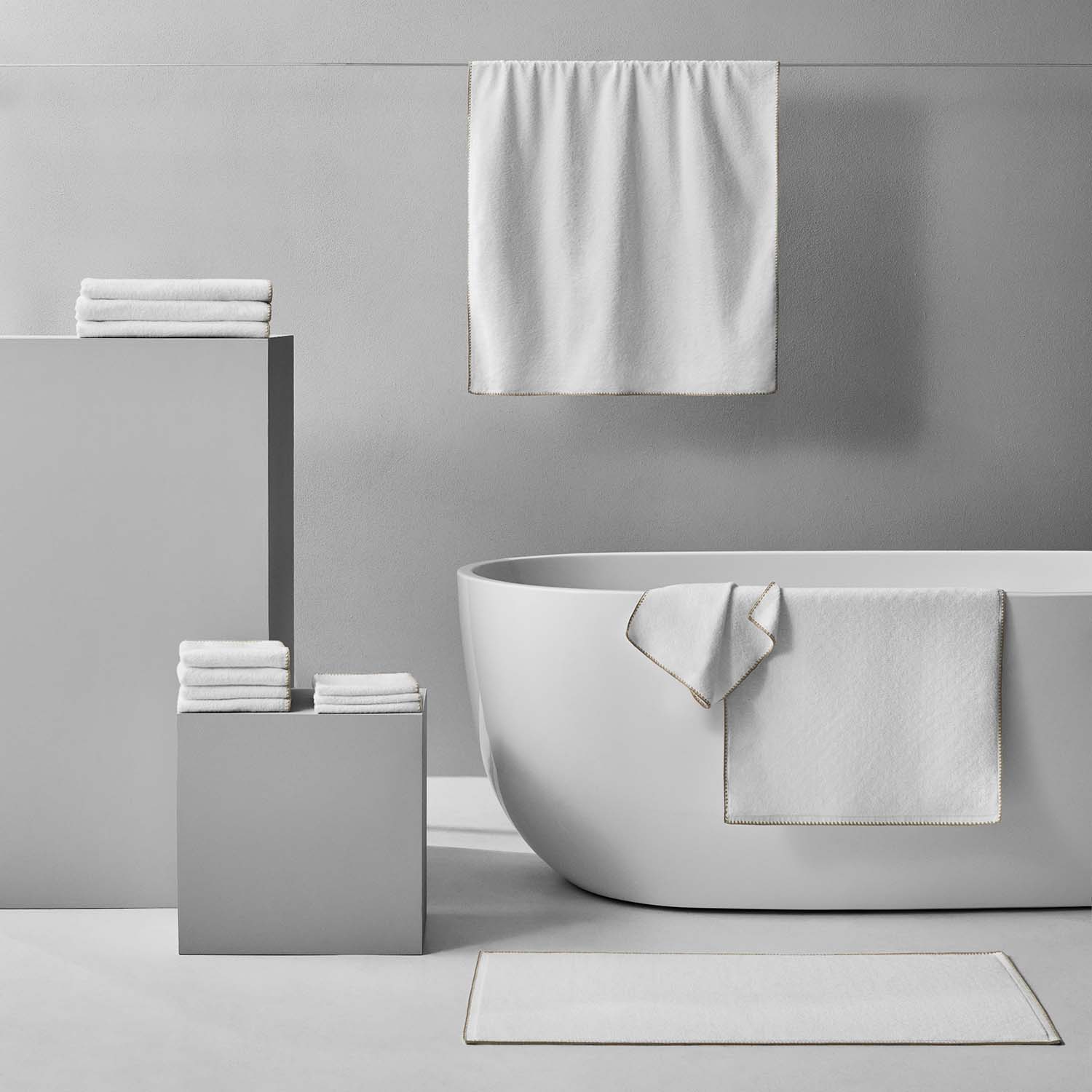 Bordado towel in sand trim displayed in a modern bathroom setting with minimalist decor.