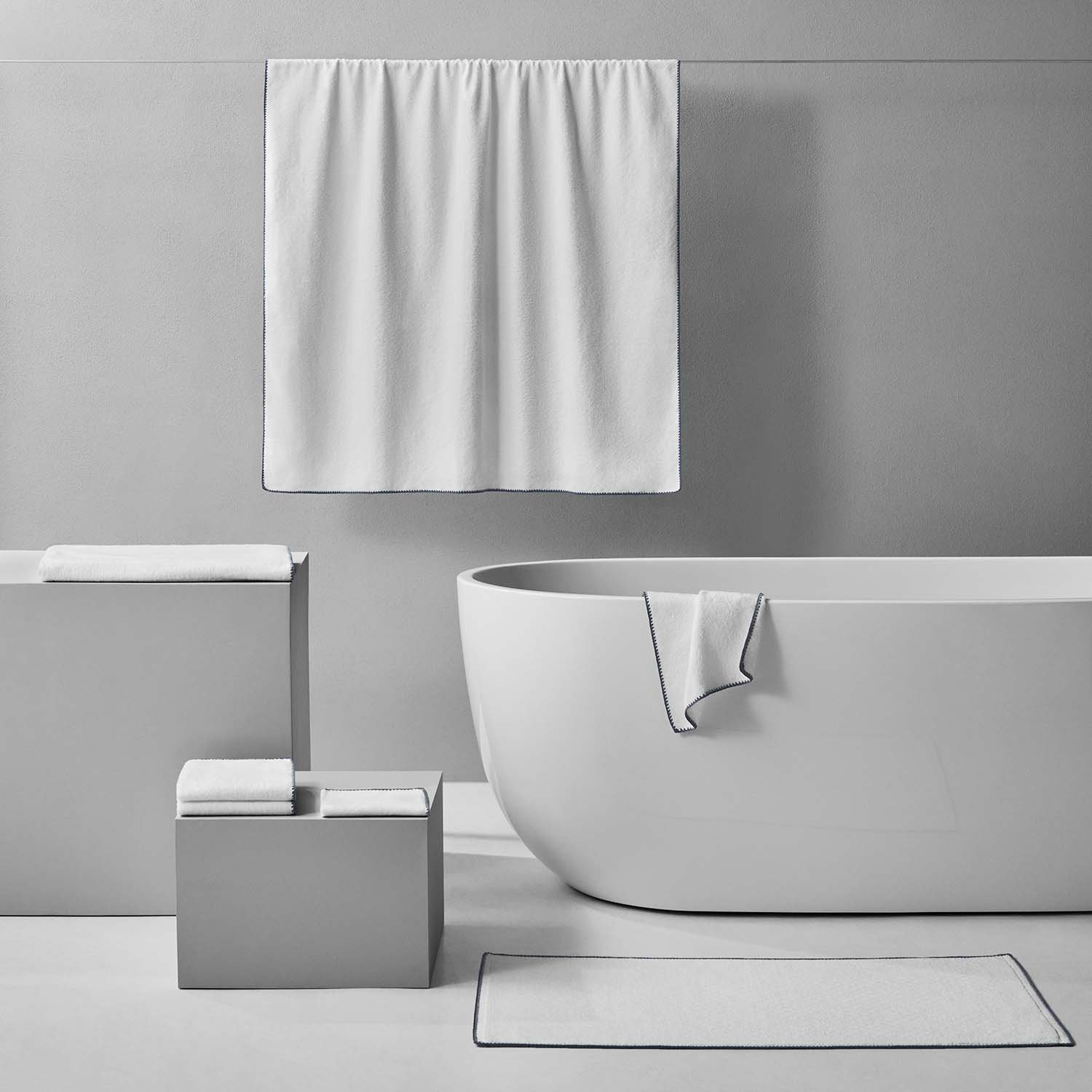 Bordado towel with grey trim displayed in a modern bathroom setting, showcasing its thin, plush design.