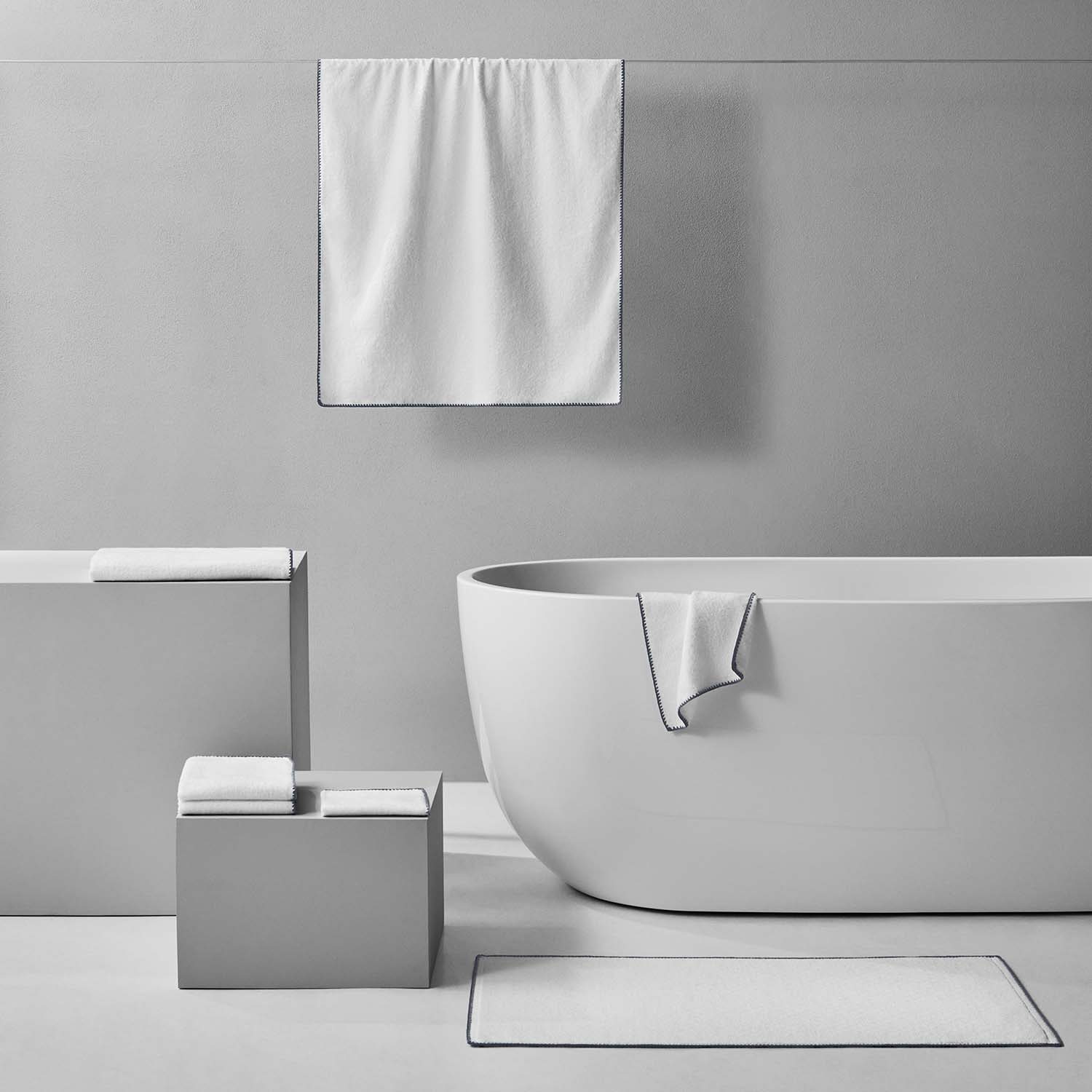 Bordado towel with grey trim displayed in a modern bathroom setting, showcasing its plush and space-saving design.
