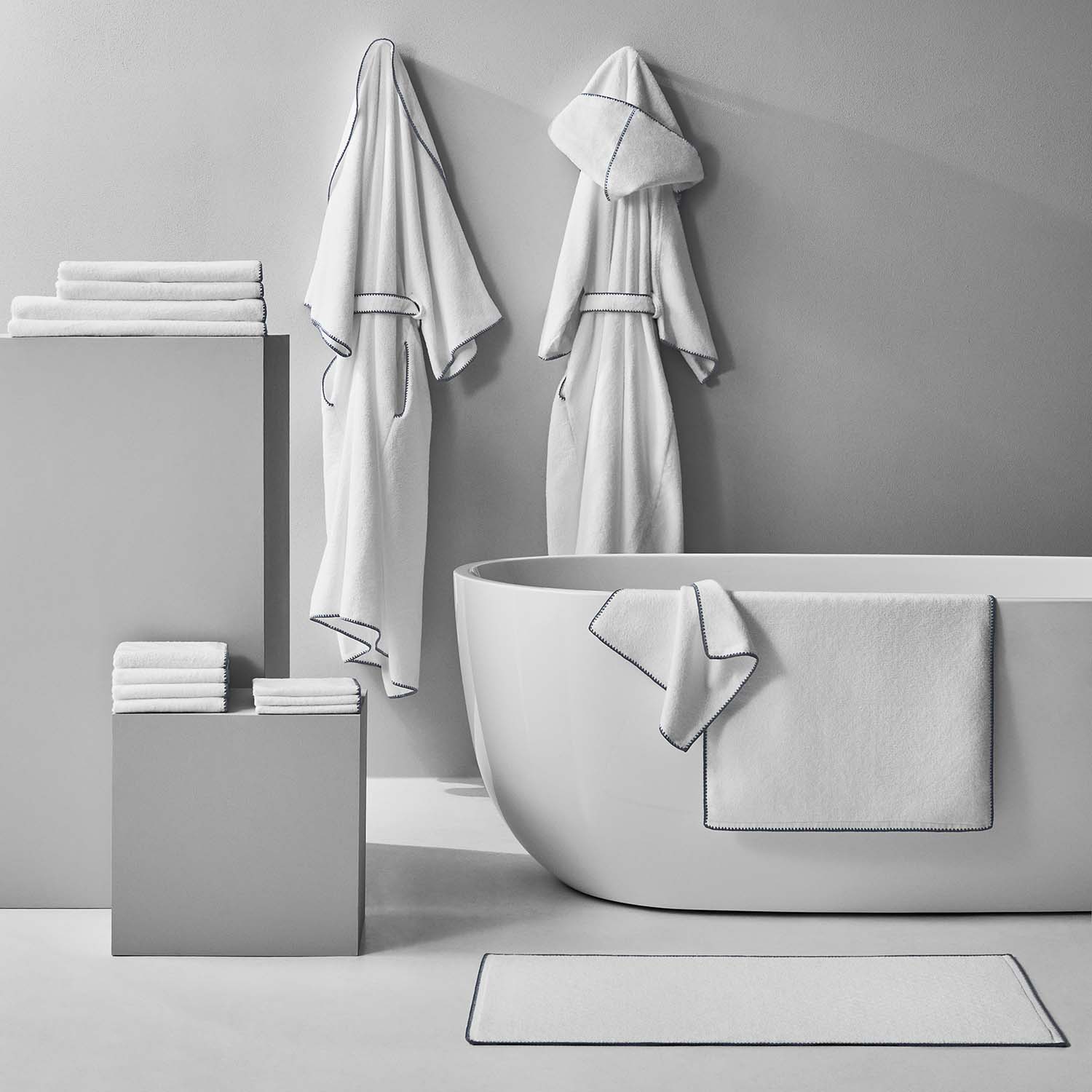 Luxurious white towels and plush bathrobes displayed in a minimalist bathroom setting, highlighting comfort and style.