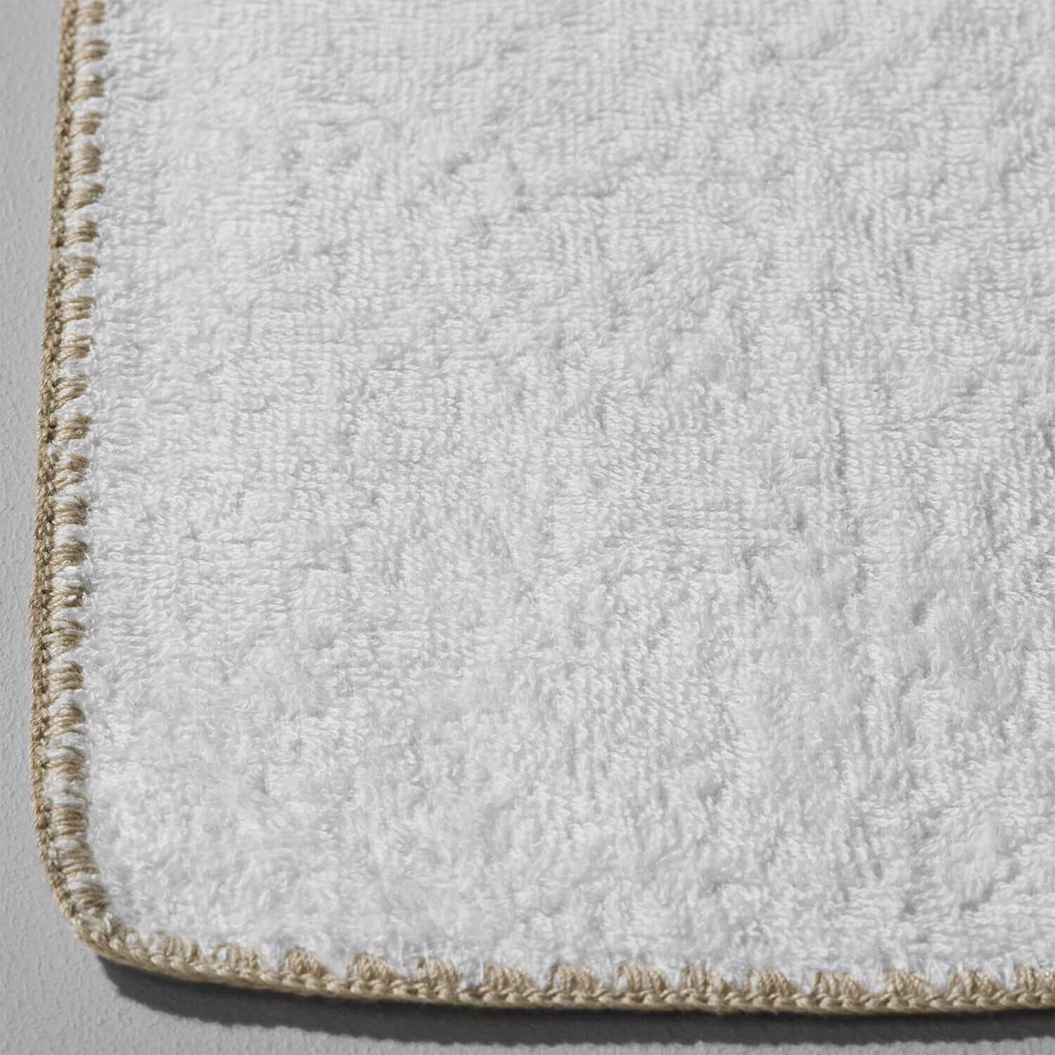 Close-up of a luxurious facial towel with sand trim, made of sustainable 100% combed cotton for spa treatments.