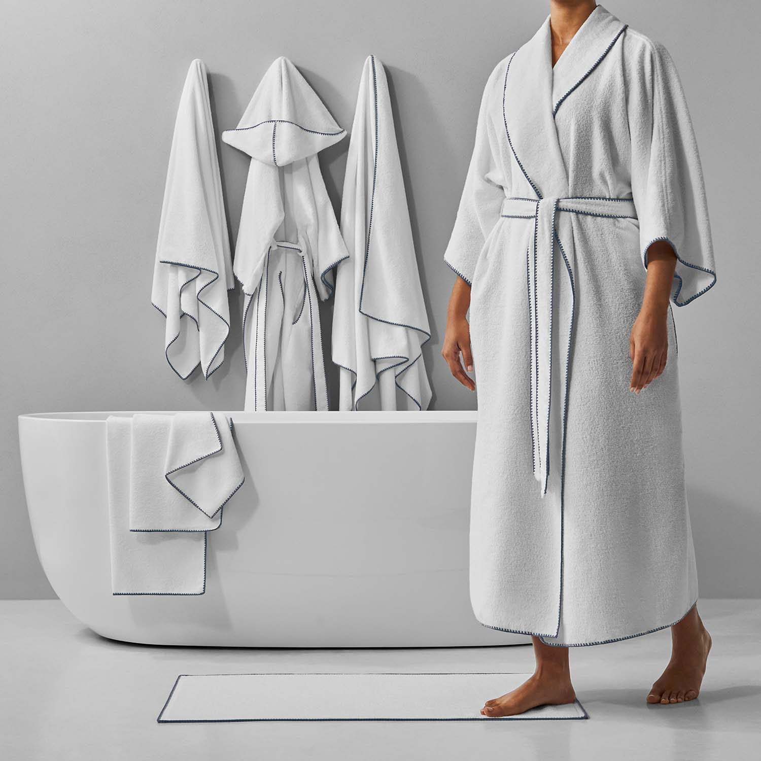 Luxurious white bathrobes and towels displayed in a modern bathroom with a sleek soaking tub.