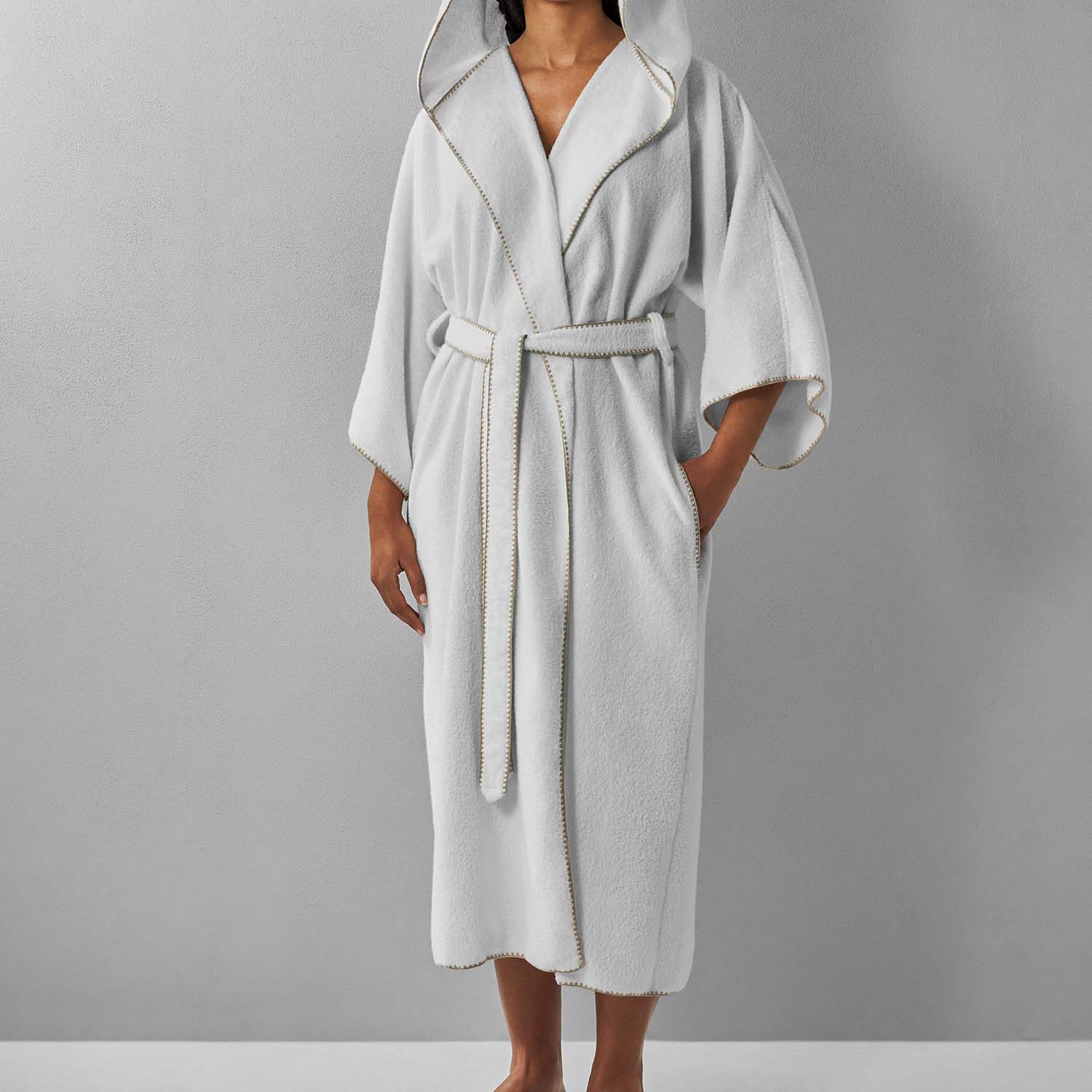 Bordado Hooded Sand Trim Bathrobe with self-tie belt, pockets, and chill-resistant hood in plush white fabric.