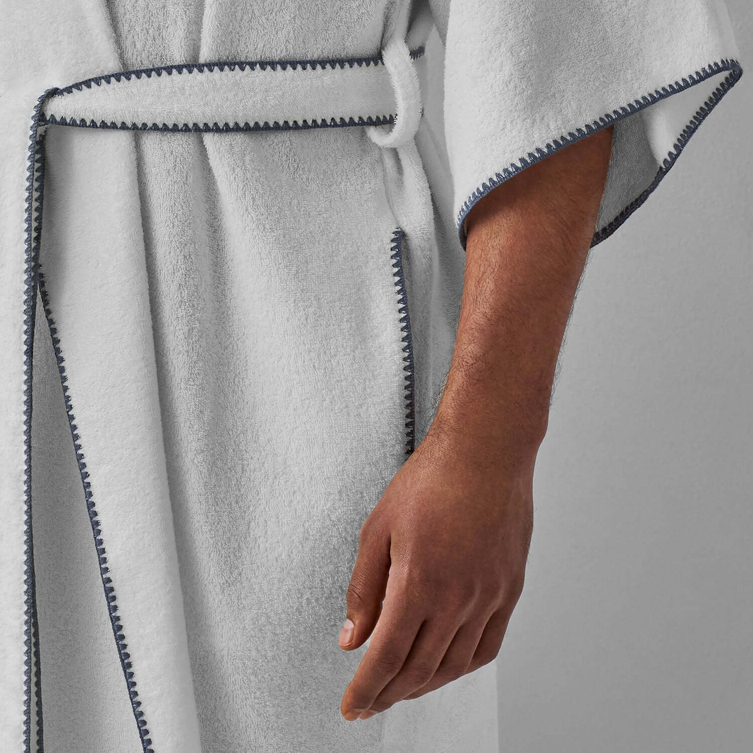 Close-up of a hand in a gray-trimmed Bordado shawl robe showcasing its modern design and plush texture.