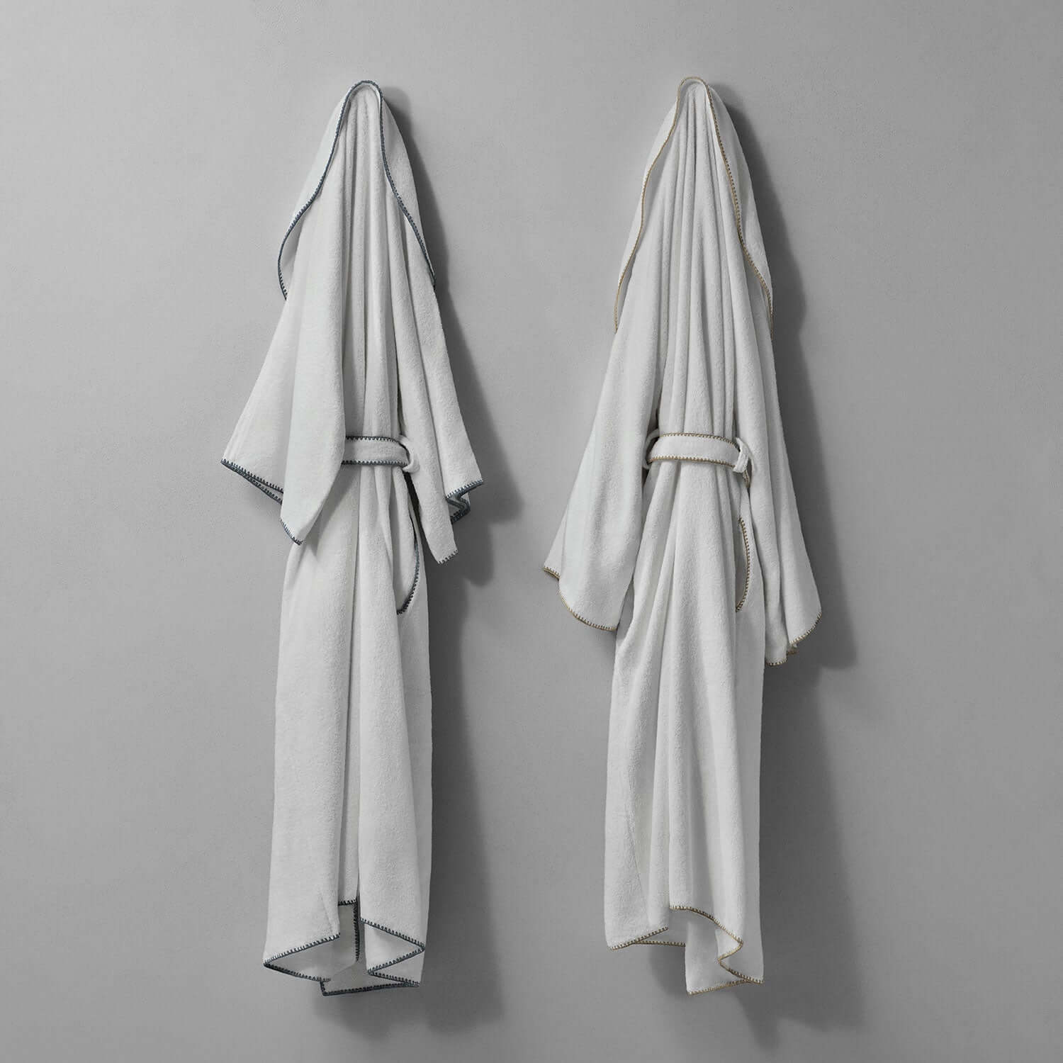 Bordado shawl with sand trim hanging against a gray wall, showcasing modern design and plush texture.