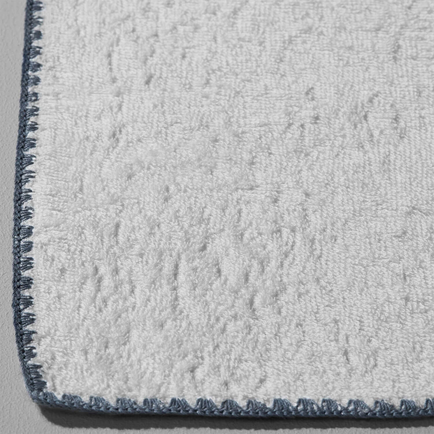Bordado towel with grey trim, space-saving design, plush texture, eco-friendly, and efficient for washing and storage.