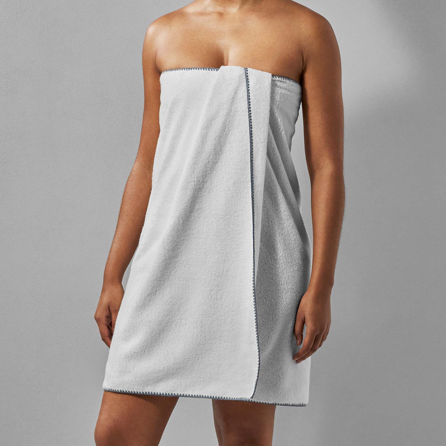 Bordado towel with grey trim, featuring a thin plush design, space-saving and eco-friendly for efficient washing.