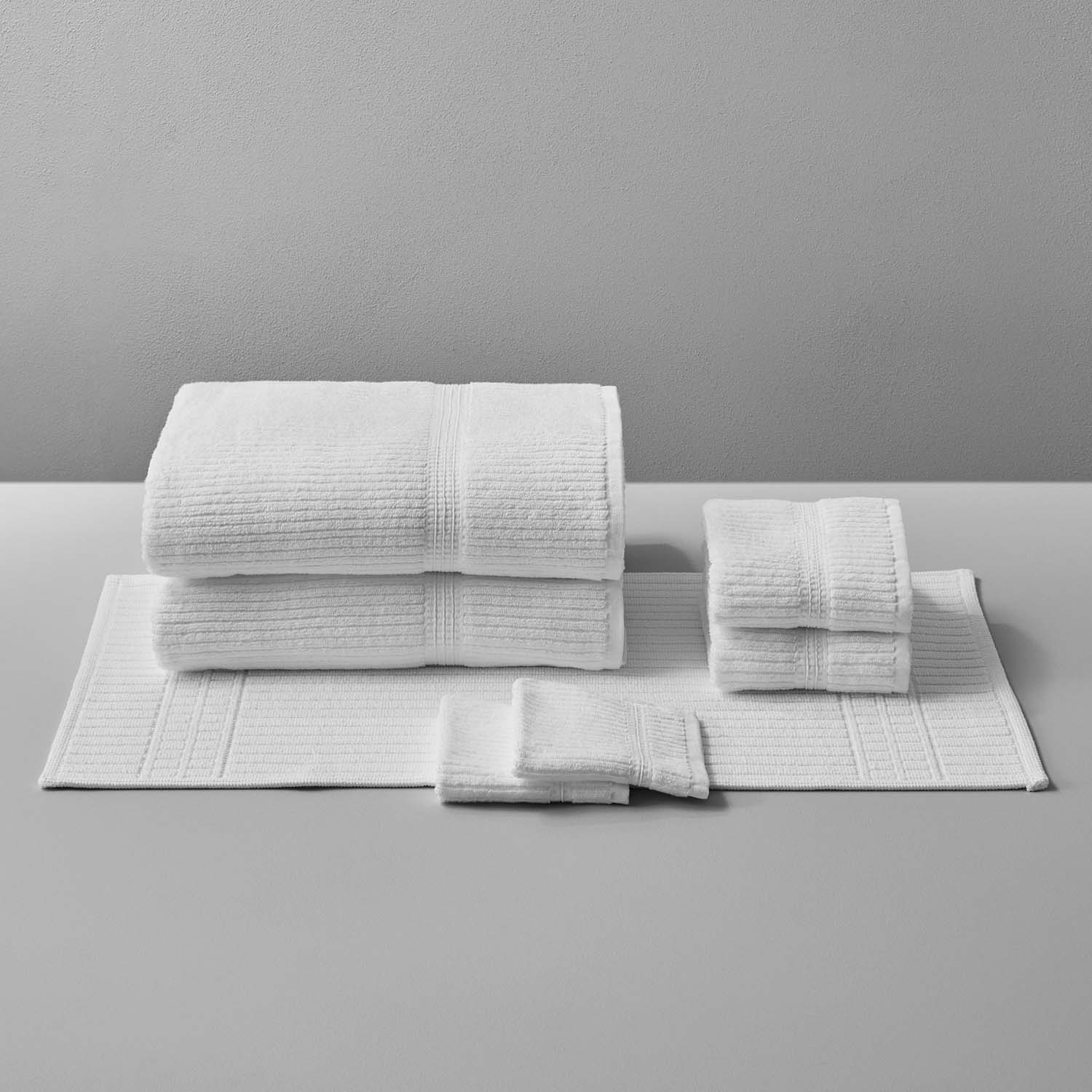 Canelado Towel set displayed on a table, perfect for daily spa rituals at home, featuring multiple sizes in white.