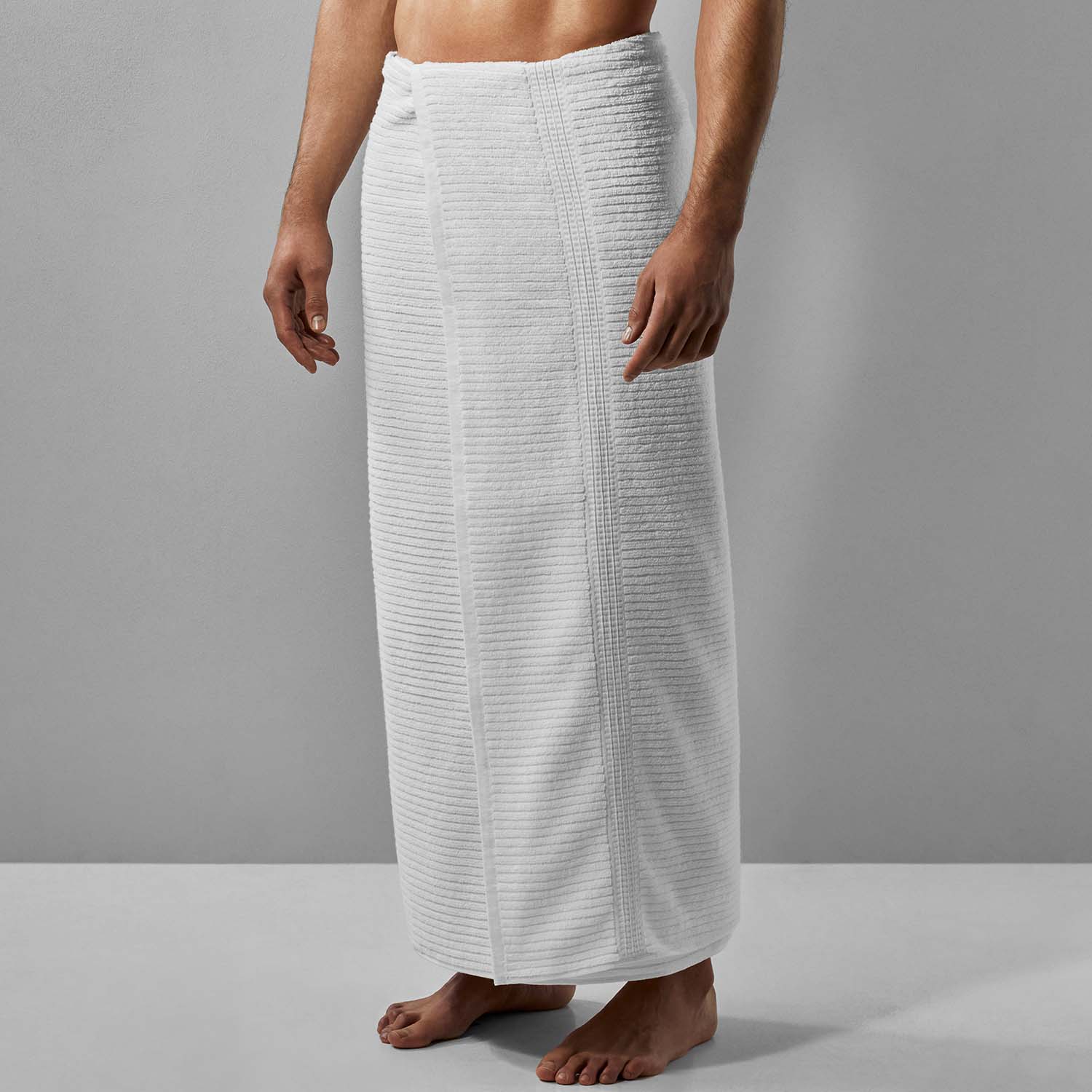 Man wearing a Canelado towel, perfect for daily spa rituals at home, featuring a textured design in pristine white.