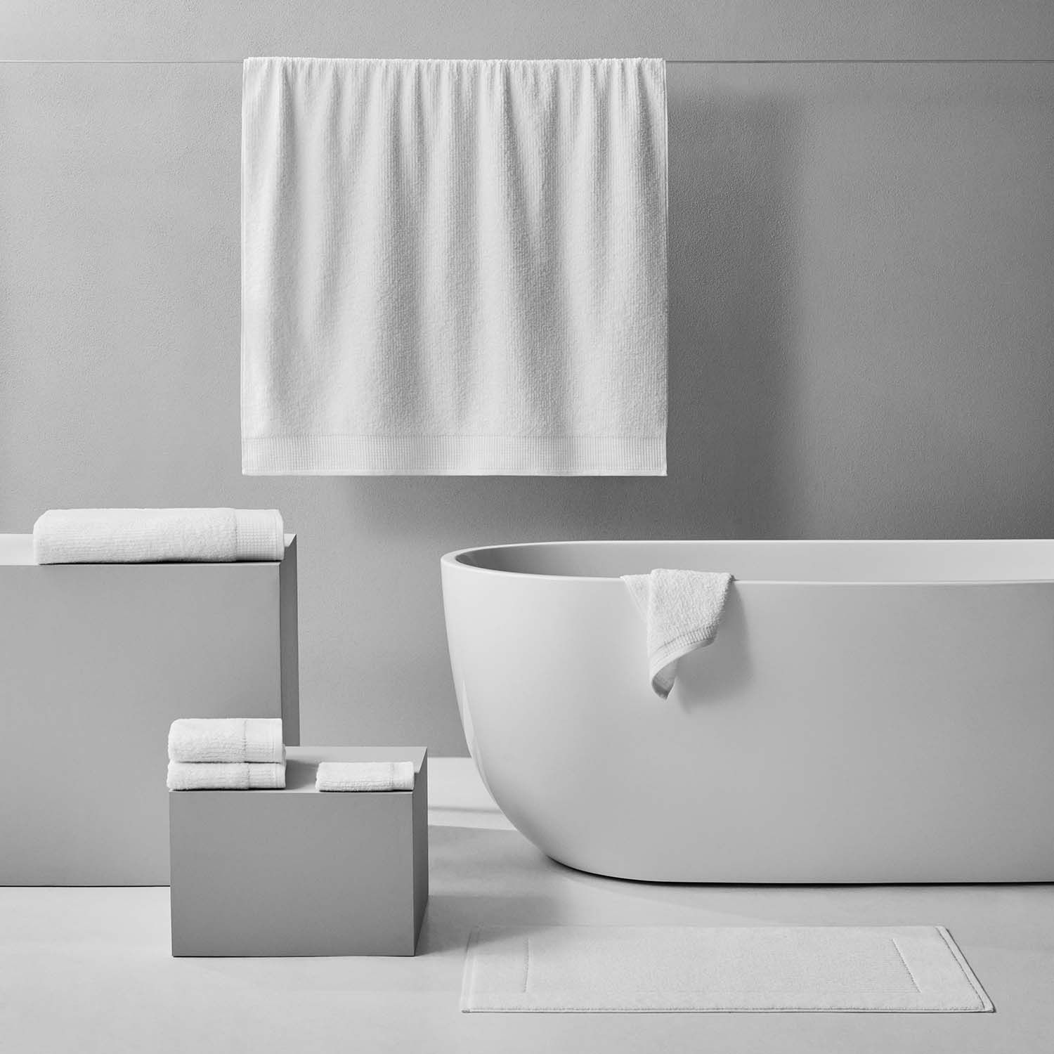 Luxor Towel display in a modern bathroom, showcasing plush white Egyptian Cotton towels and a sleek bathtub.