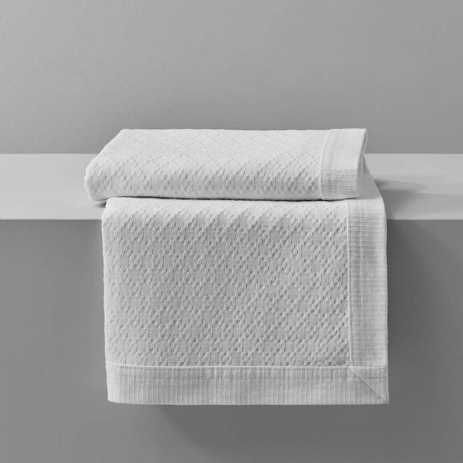 Luxurious white cotton towels folded on a shelf, showcasing a classic textured design for elegant bathroom decor.