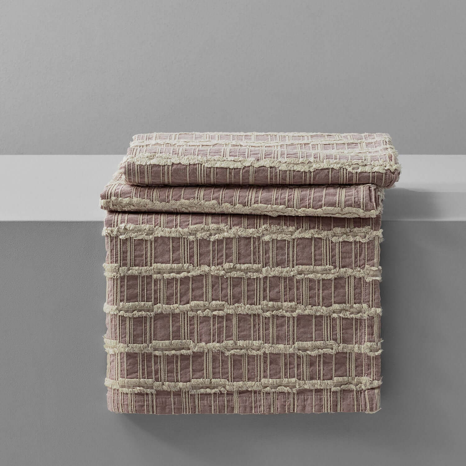 Lattice blanket in light rose and salmon colors with criss-cross fringe pattern, perfect for eco-chic decor.