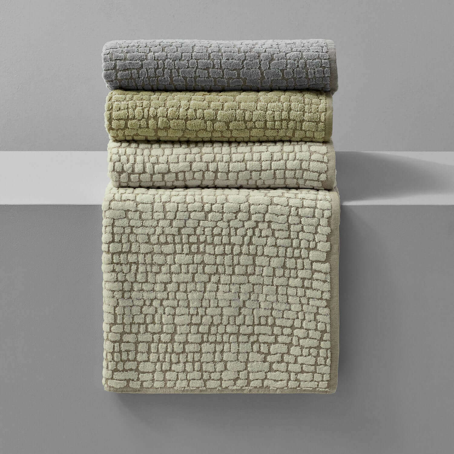 Pebble blanket collection in gray, green, and beige tones, showcasing natural texture and cotton softness.