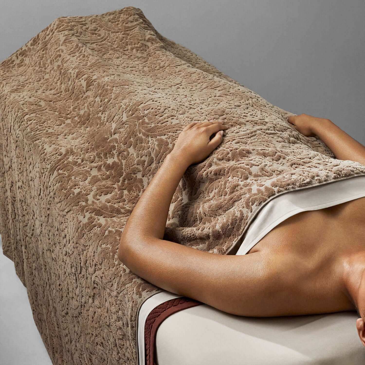 Baroque Chocolate blanket draping over a massage table, showcasing the soft, supple velour texture for a luxurious experience.