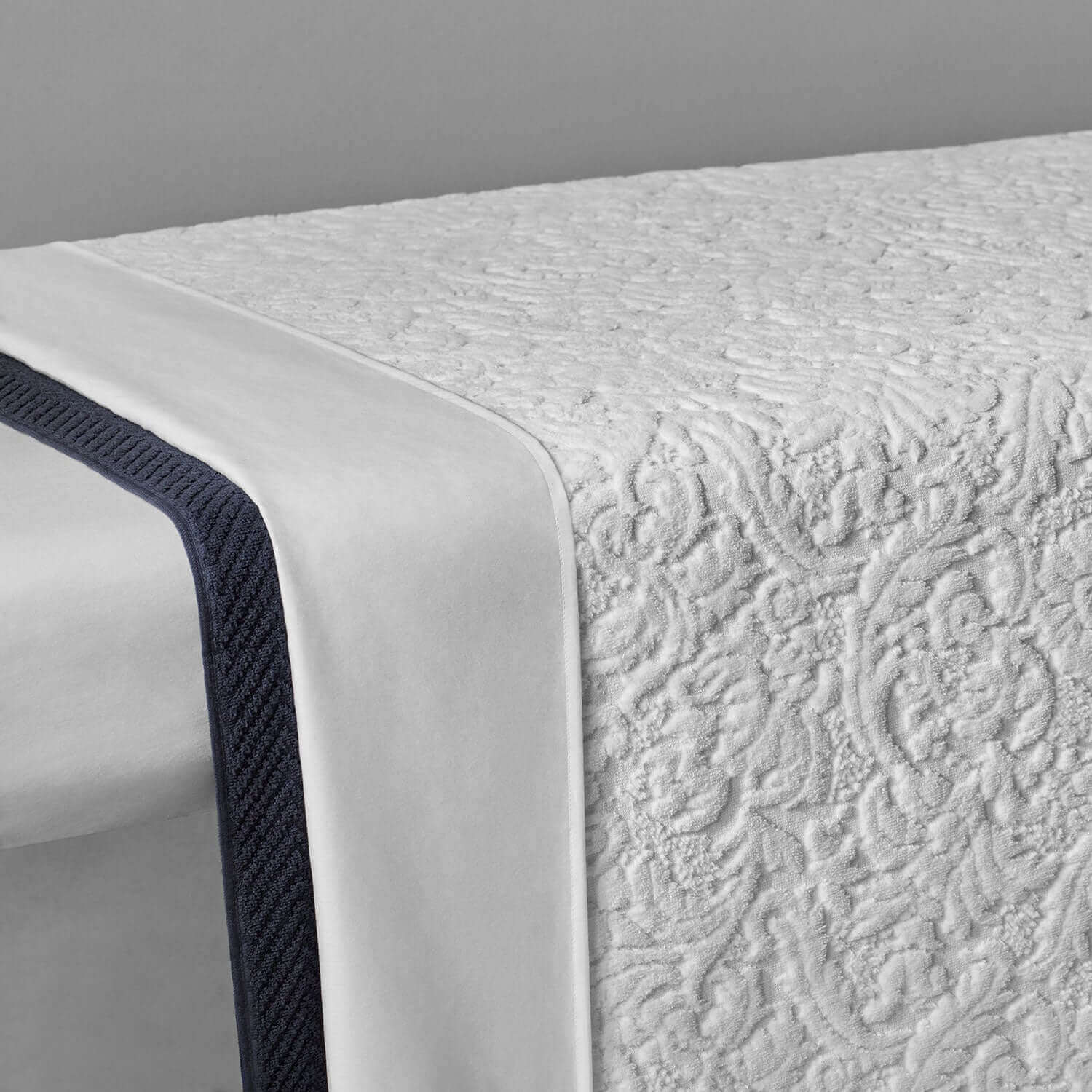 White Baroque blanket showcasing a luxurious velour pattern with dark trim on the edge.