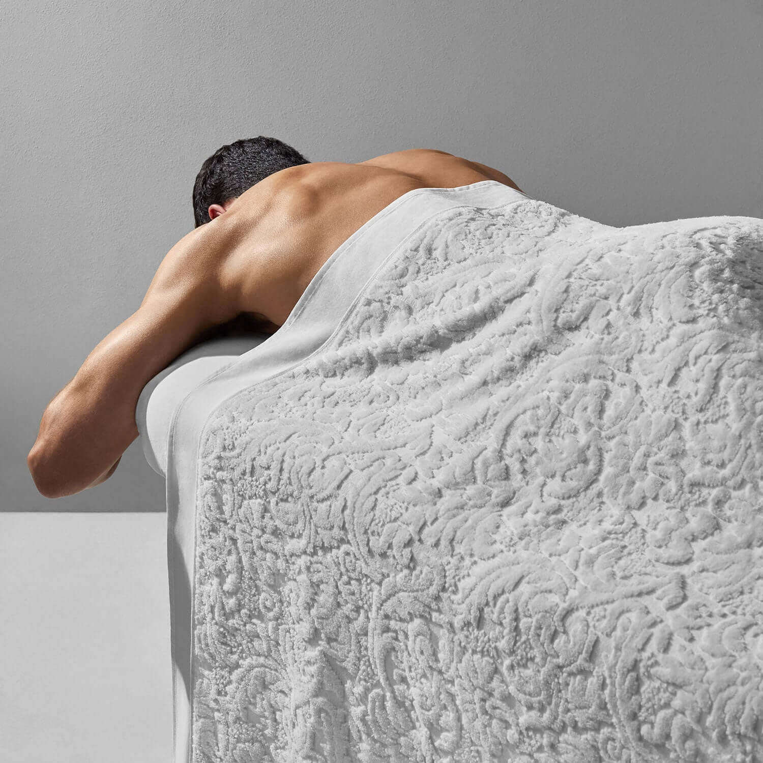 Man relaxing with a luxurious white Baroque blanket, showcasing its plush velour texture and elegant design.