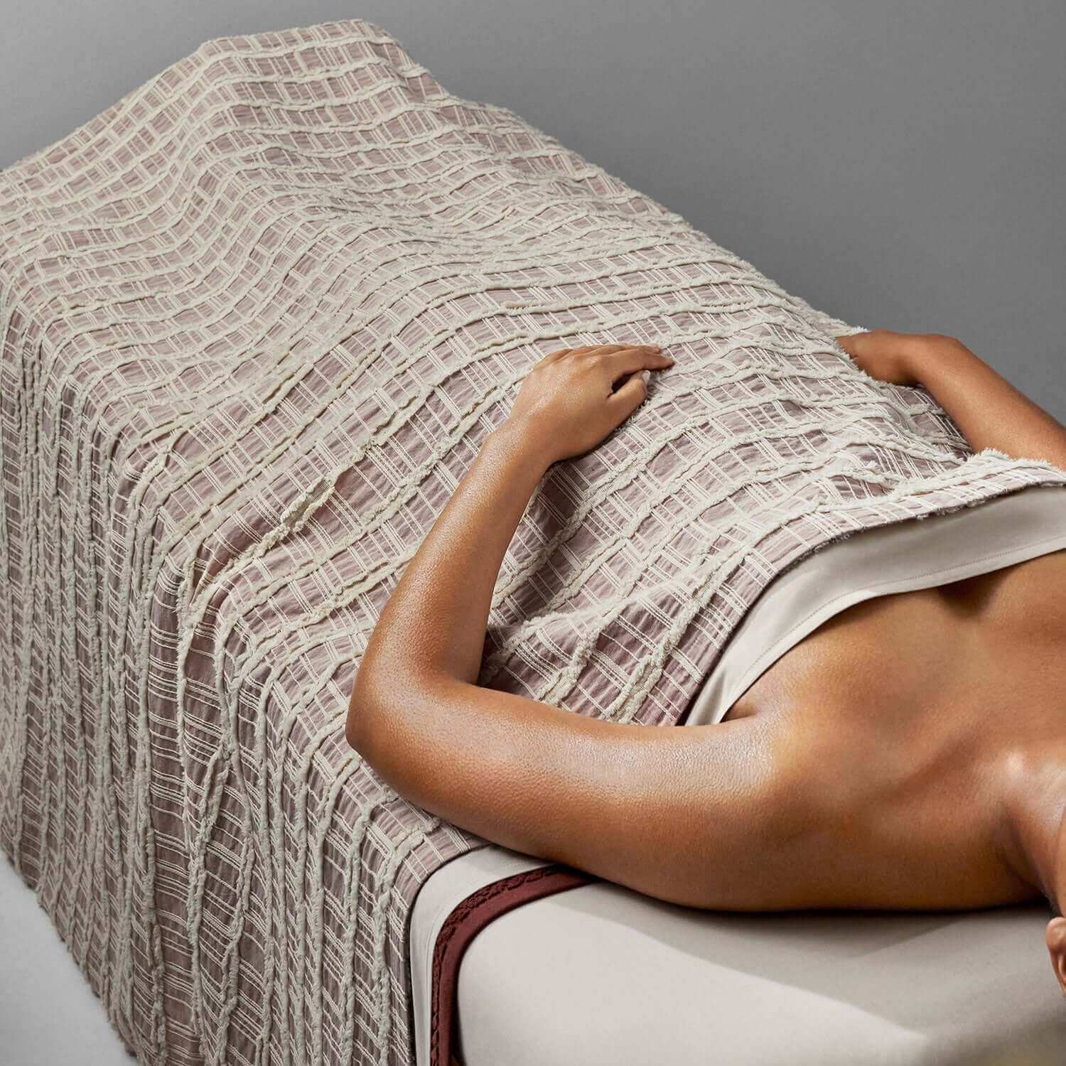 Lattice blanket in light rose and salmon draped over a spa table, showcasing eco-chic craftsmanship and design.