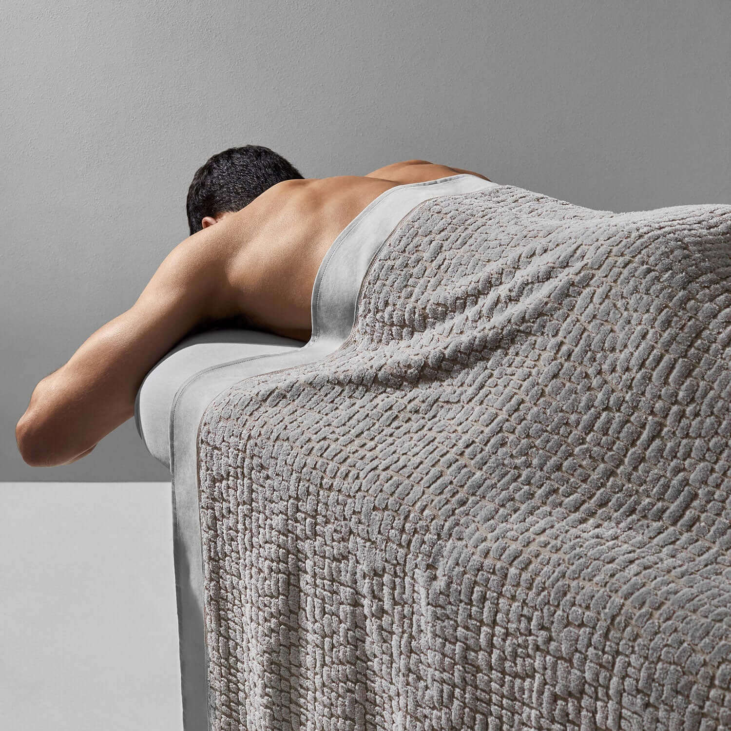 Pebble blanket in gray draped over a spa table, providing comfort and relaxation during treatment.