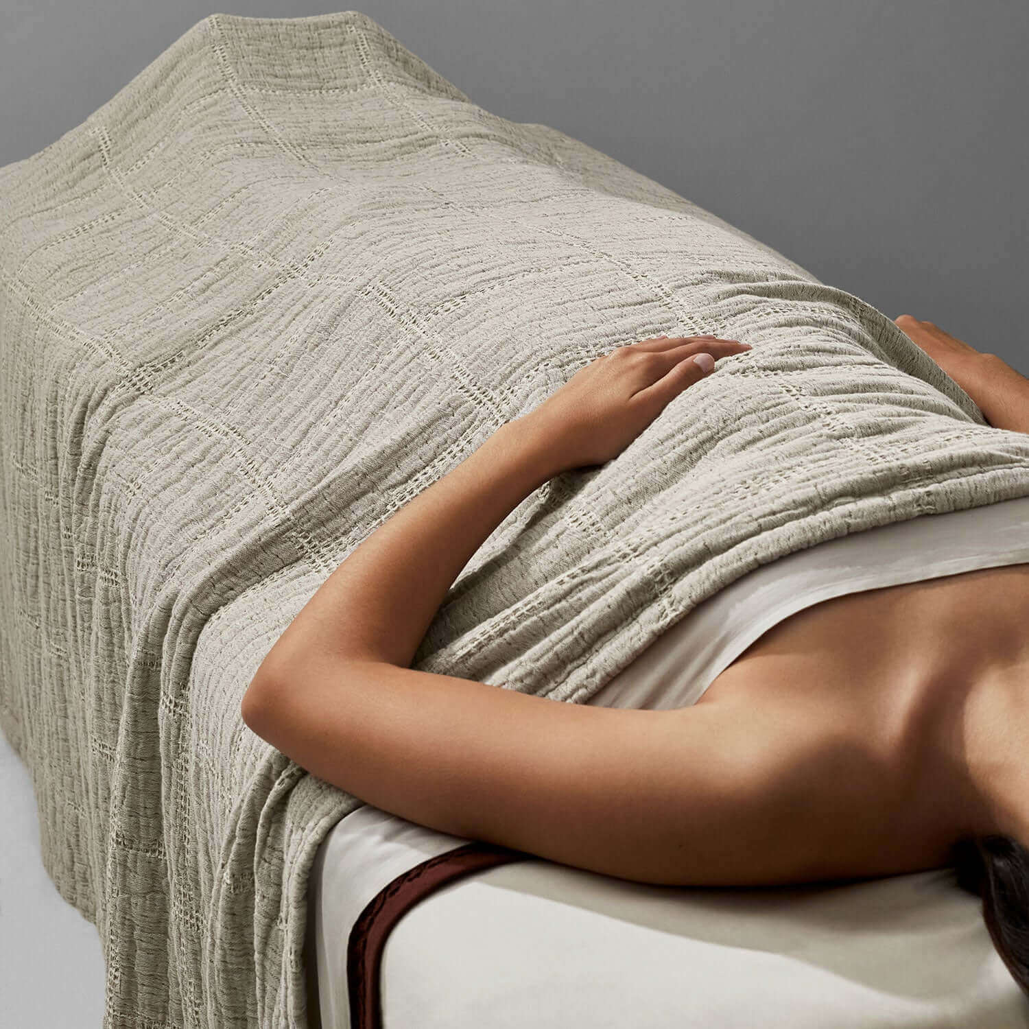 Serene stitch blanket in soft stone-beige tones, wrapping a spa treatment for a touch of eco-luxury comfort.