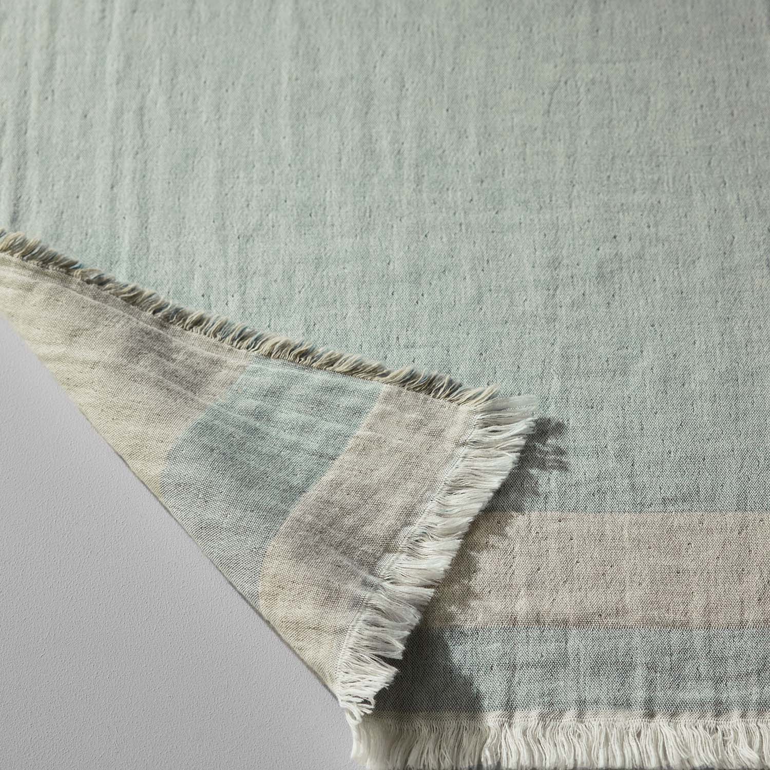 Two-toned, three-layered Cenote blanket featuring eco-chic fringed edges, ideal for hotels and resorts.