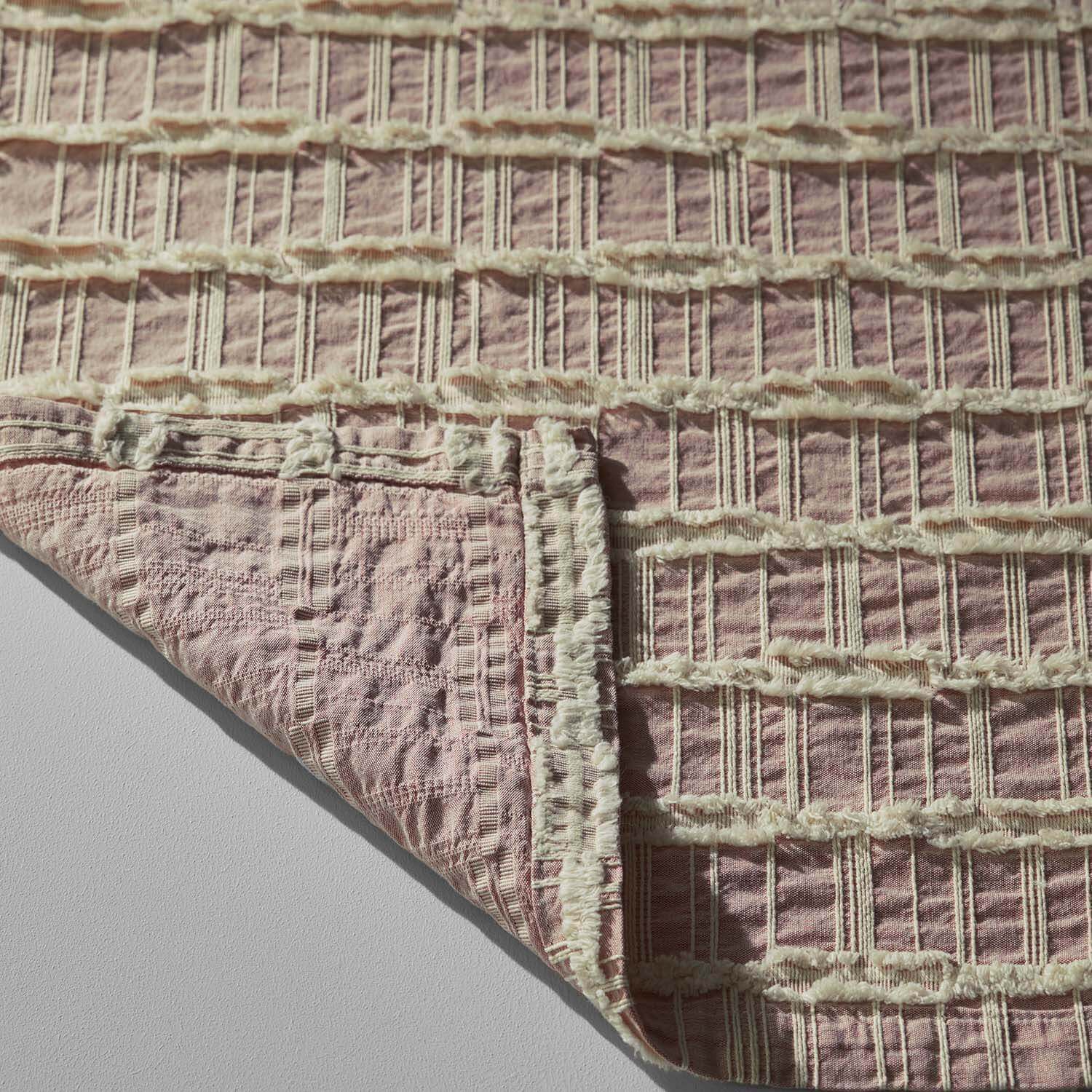Lattice Blanket in light rose and salmon with intricate criss-cross patterns, ideal for eco-chic hotels and spas.