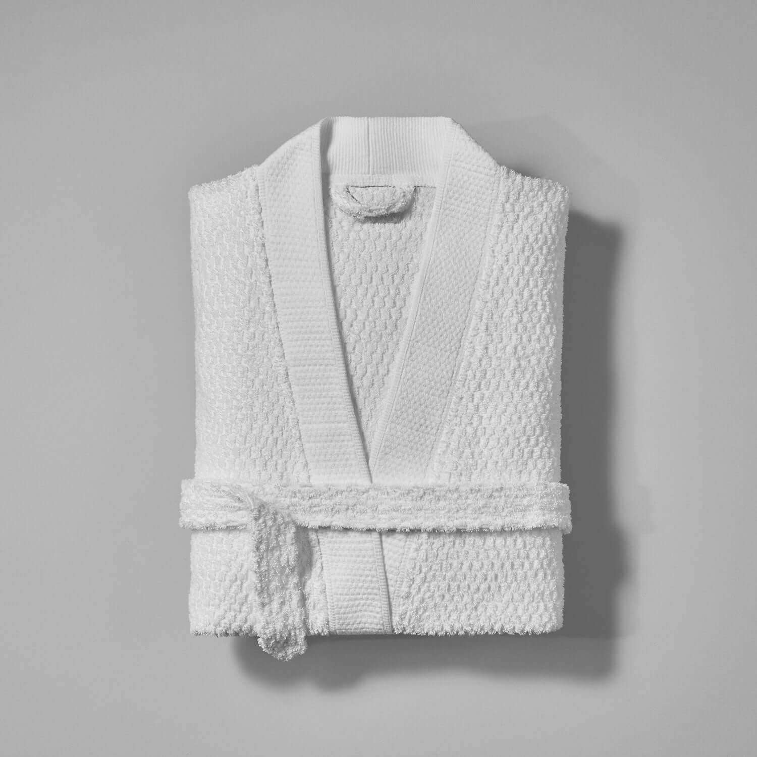 Folded white Novotel Jacquard kimono robe with braided detail and soft-touch biconcave pattern, perfect for spas and country clubs.