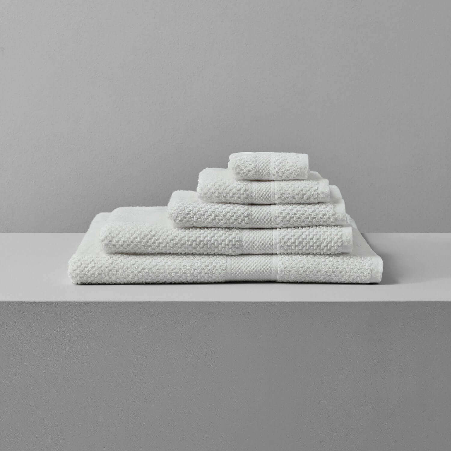 Novotel Towel collection displayed on a shelf, featuring plush, sporty luxury towels made from sustainable Brazilian cotton.