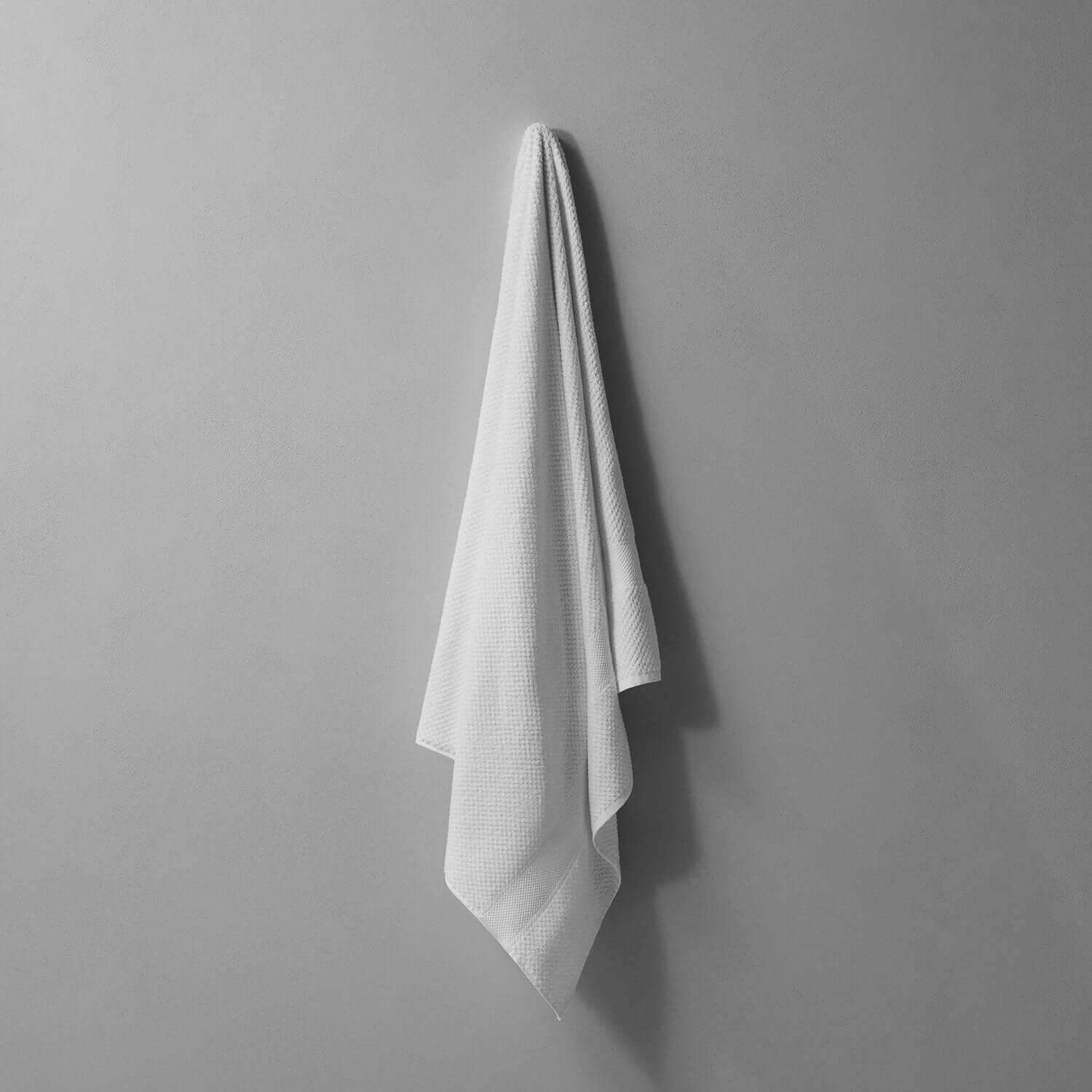 Novotel Towel hanging against a gray wall, made from 100% long-fibre Brazilian cotton for sporty luxury and performance.