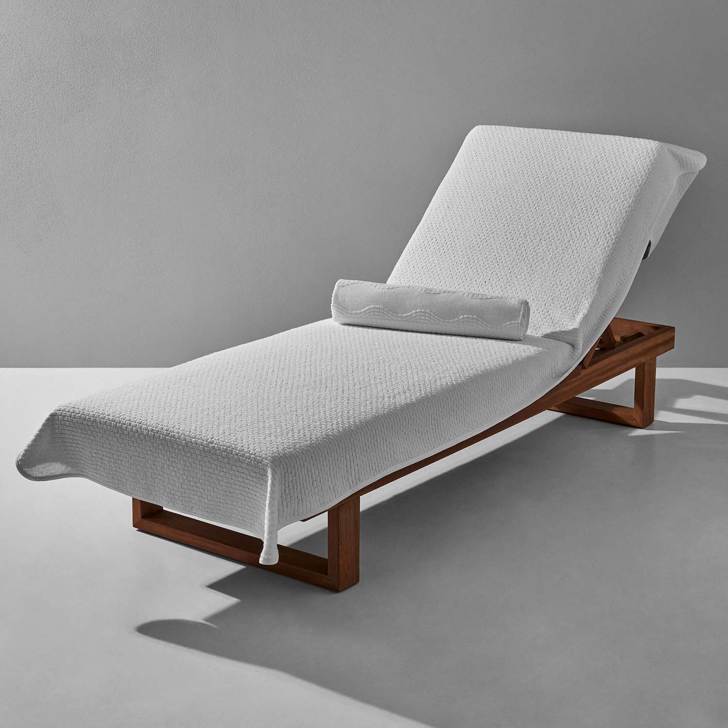 White textured lounge chair cover on a wooden frame, perfect for poolside relaxation and comfort.