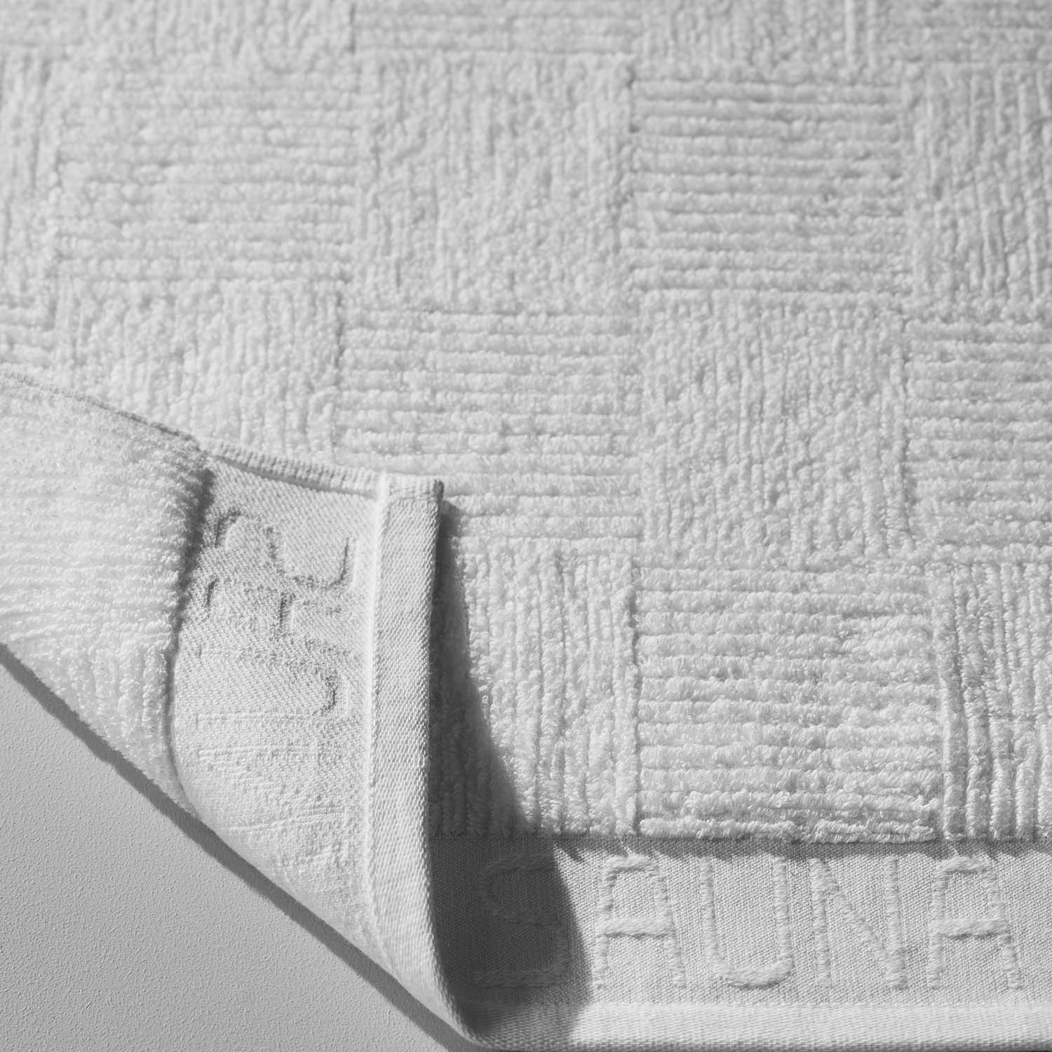 White sauna towel with textured pattern, designed for comfort and absorbency in saunas or steam rooms.
