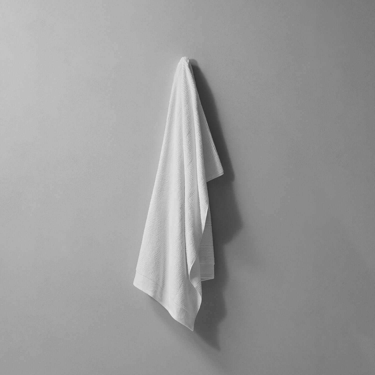 Plush sauna towel hanging on a gray wall, designed for maximum absorbency and body comfort.