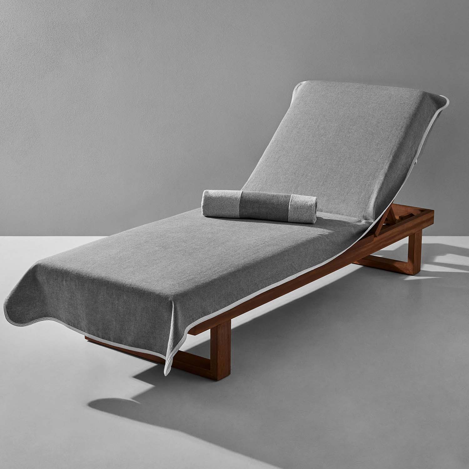 Gray lounge chair cover with matching bolster on a wooden chaise, ideal for poolside relaxation and comfort.