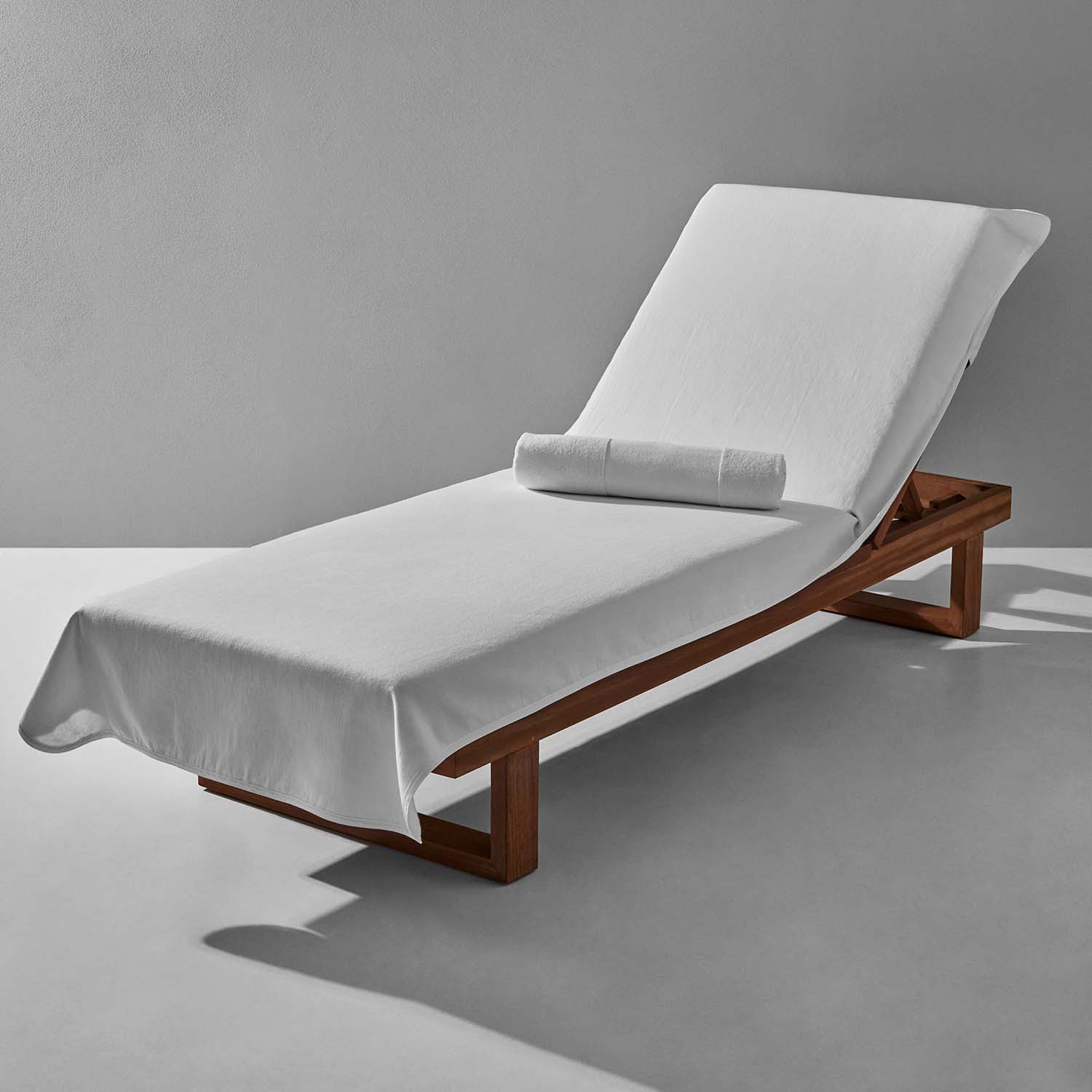 SOL Lounge Chair Cover in white, elegantly draped over a wooden recliner, ideal for resort and spa settings.