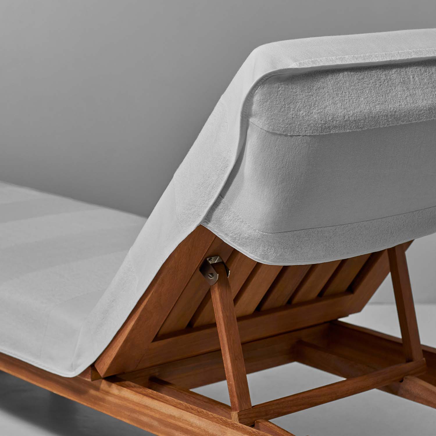White striped lounge chair cover on wooden lounge chair, designed for secure fit and comfort by the pool.