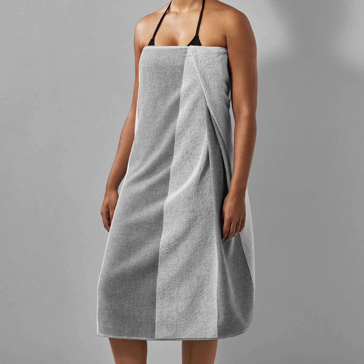 Model showcasing SOL Striped Gray Towel, eco-friendly and perfect for beach, pool, and sports activities.