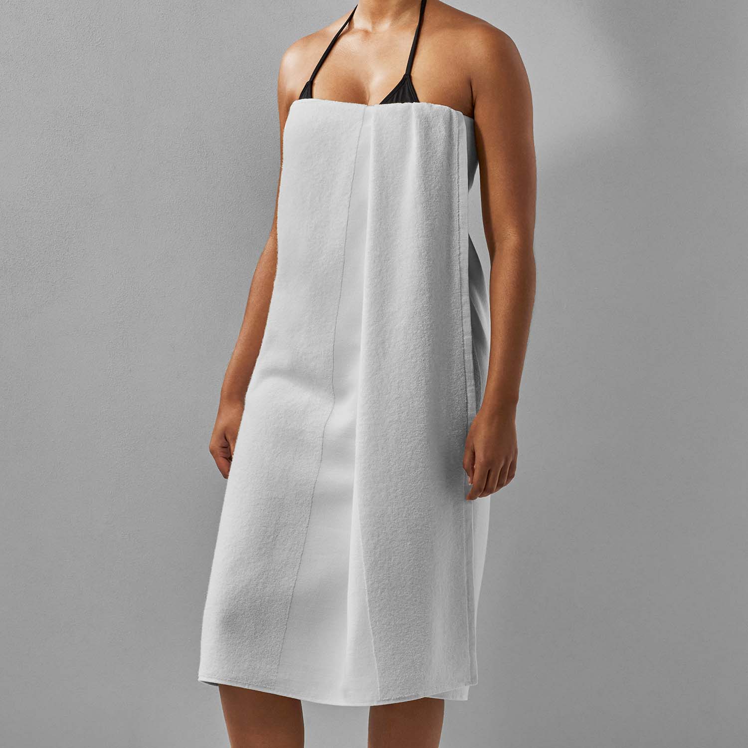 Model wearing a SOL striped white towel, showcasing its eco-friendly design for beach, pool, and sports activities.