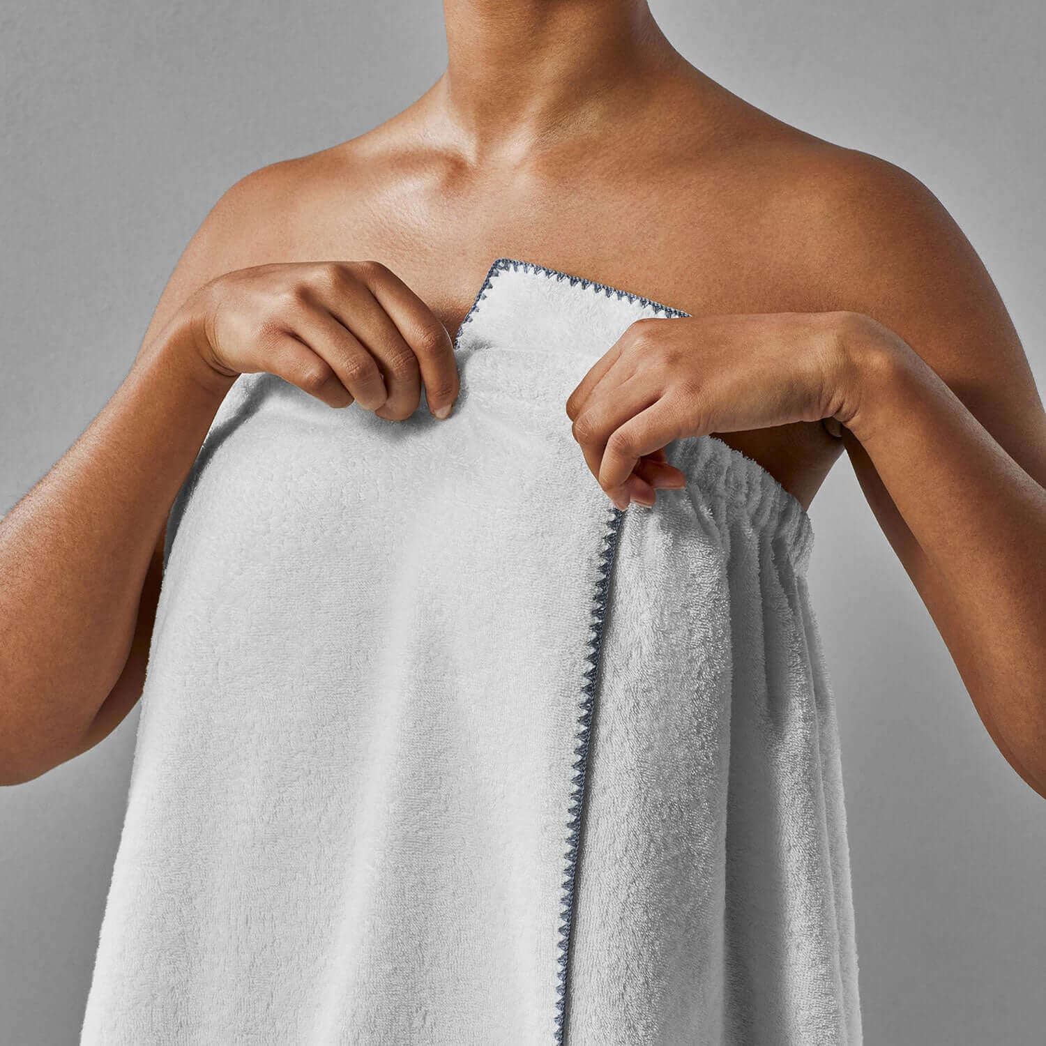 Woman adjusting a lightweight Bordado Body Wrap, showcasing versatile unisex design for spa or morning rituals.
