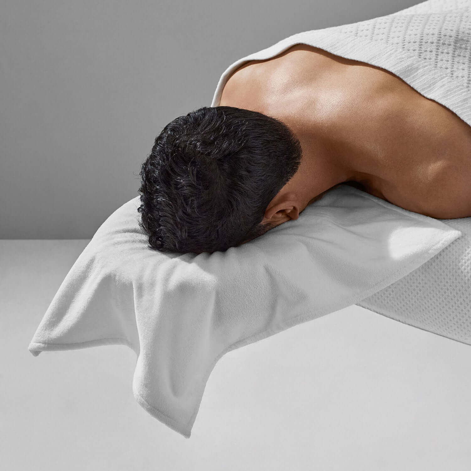 Man relaxing on a massage table with a plush, soft pillow cover for ultimate comfort and support.