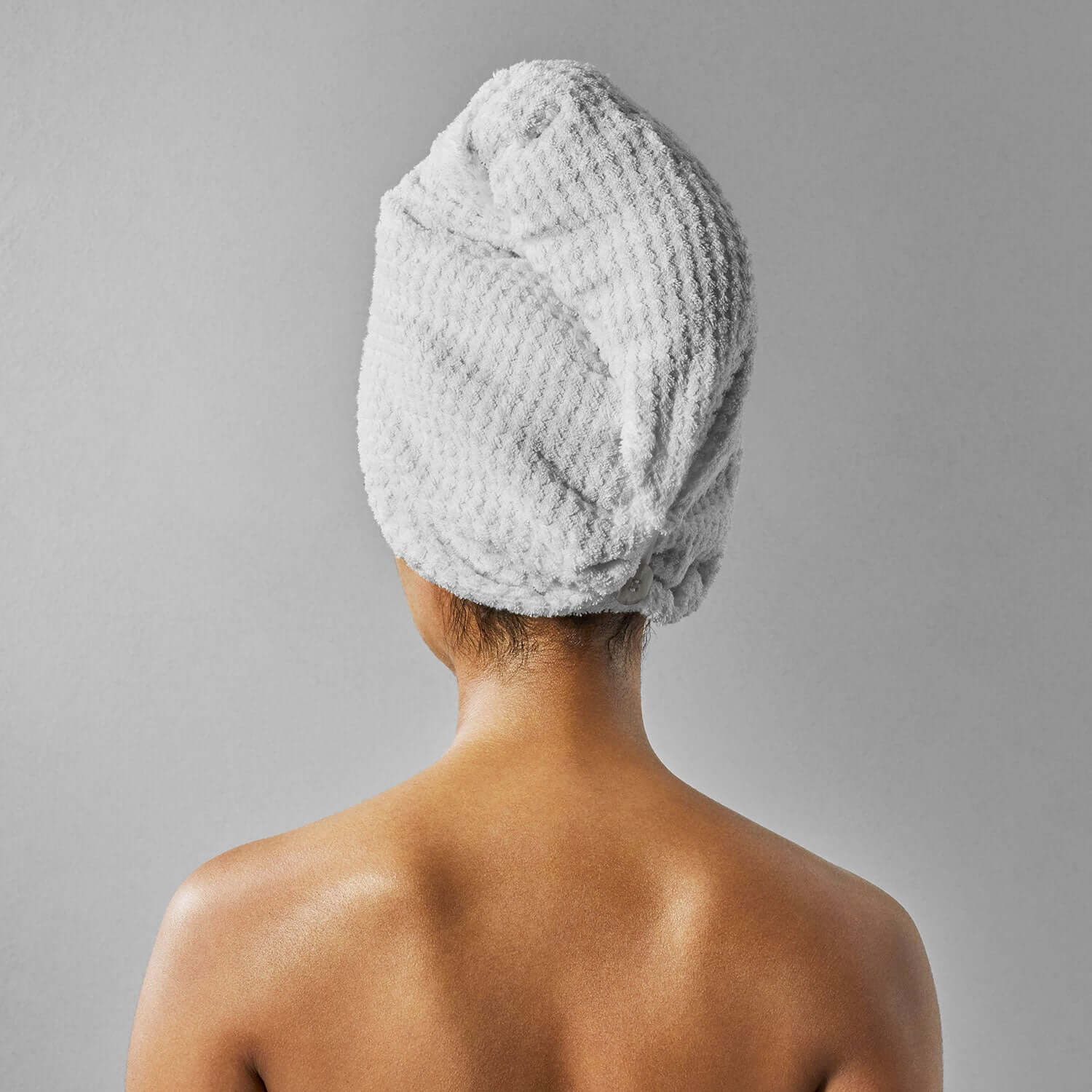 Back view of a person wearing a gray dimpled biconcave patterned turban towel, showcasing its chic and stylish design.