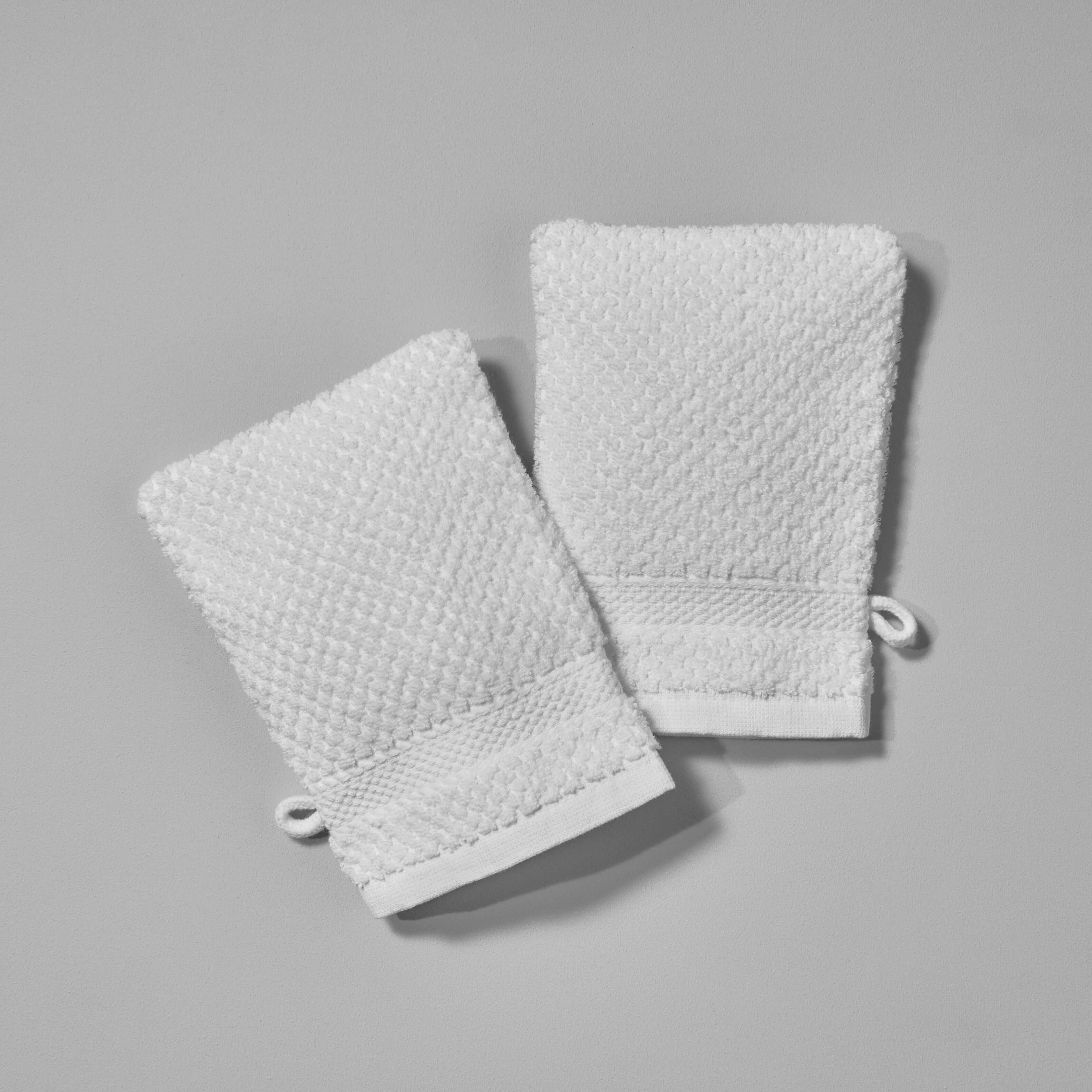 Two textured white body gloves designed for exfoliation, perfect for spas and hotels for enhanced skincare routines.