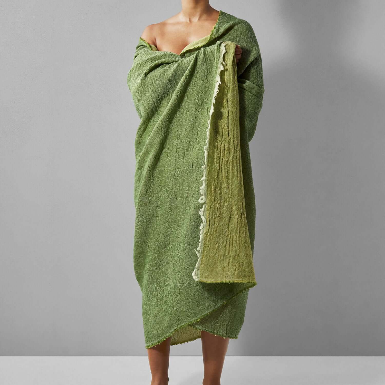 Model draped in a two-tone reversible Merino throw in grass green, showcasing fine Italian wool craftsmanship.