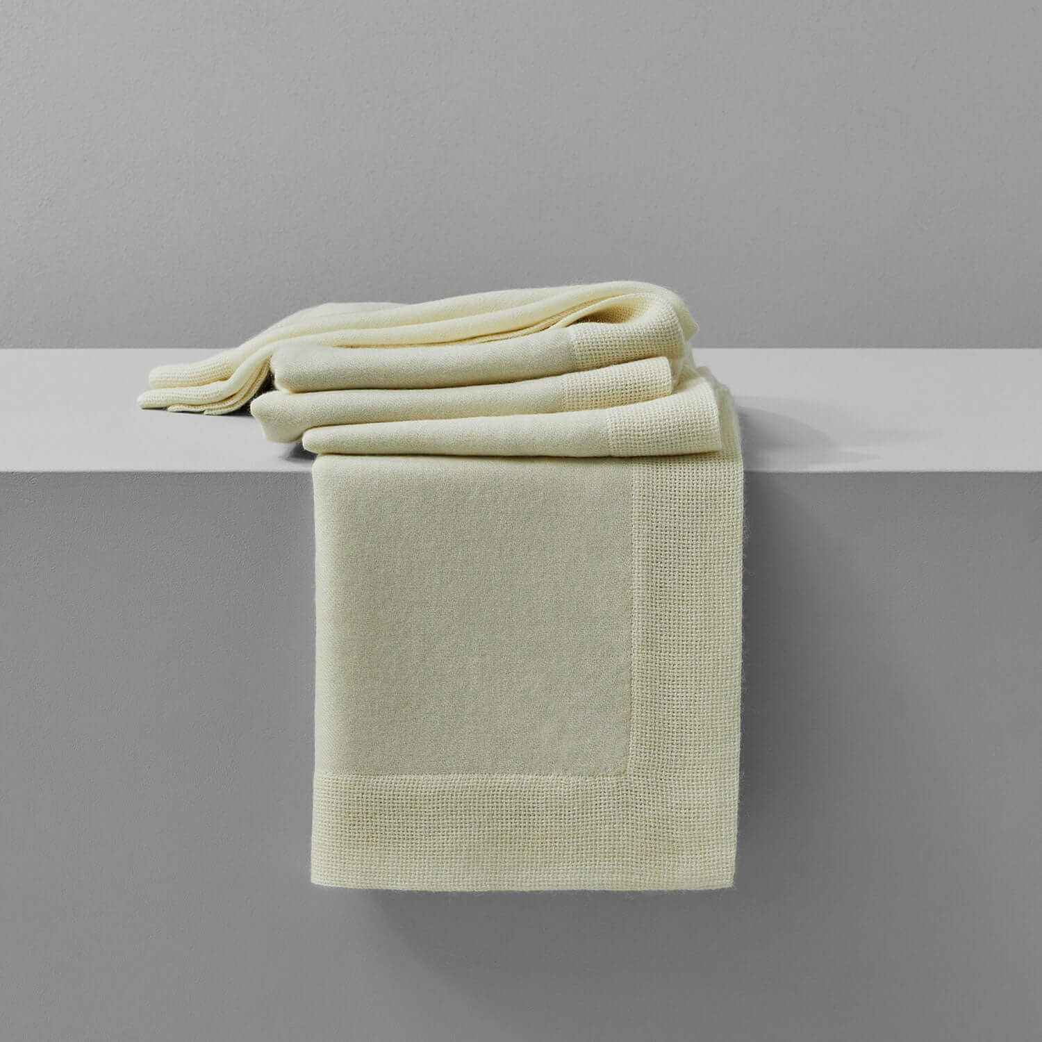 Soft Baby Alpaca throw in cream color, elegantly draped on a shelf, showcasing luxurious comfort and warmth.