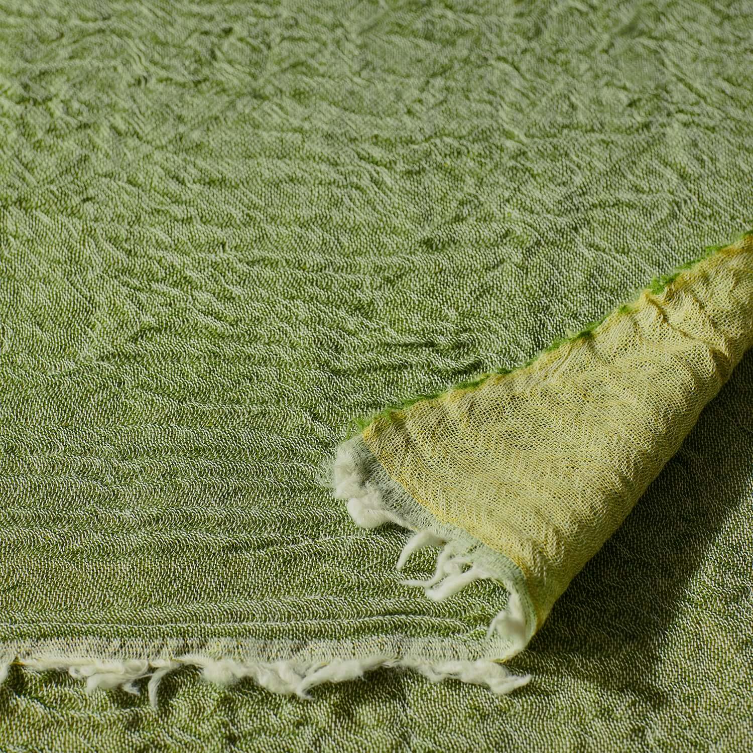 Close-up of a luxurious two-tone reversible Merino throw in grass green, highlighting fine Italian wool craftsmanship.