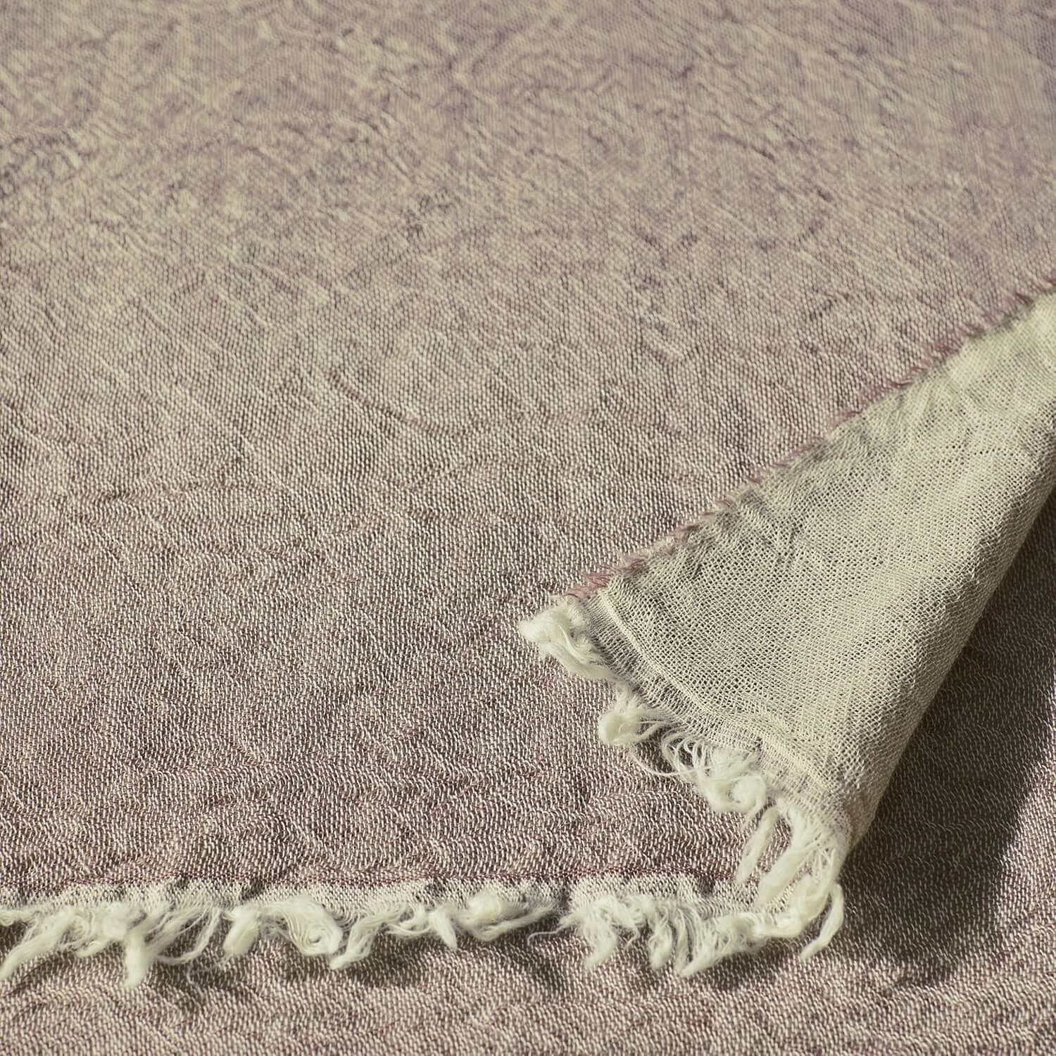 Close-up of a mauve Merino throw showcasing its two-tone reversible weave and delicate fringe.