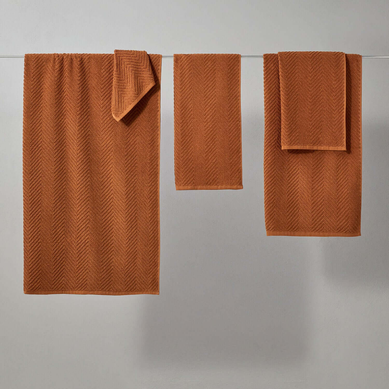 Set of clay treatment towels in warm orange, designed for spa use, featuring a herringbone pattern.