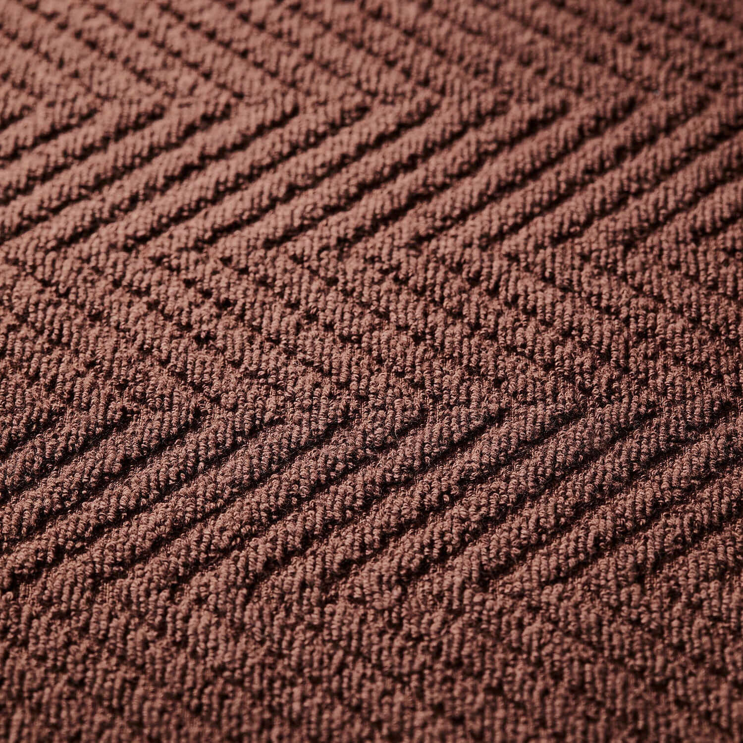 Close-up of textured brown treatment towel, designed for spa clay and mud treatments, showcasing a sophisticated herringbone pattern.